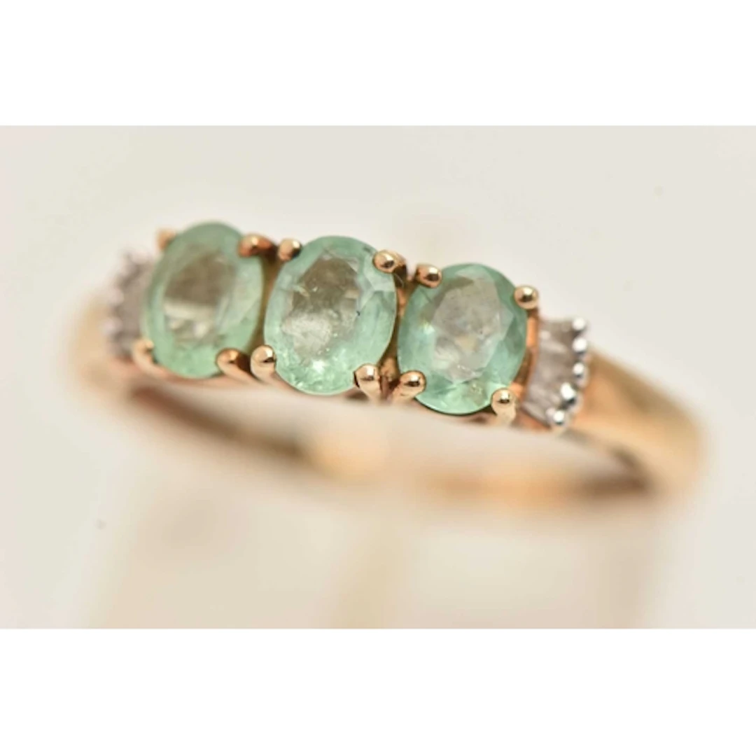 A 9CT YELLOW GOLD GEM SET RING, three light blue green oval ...