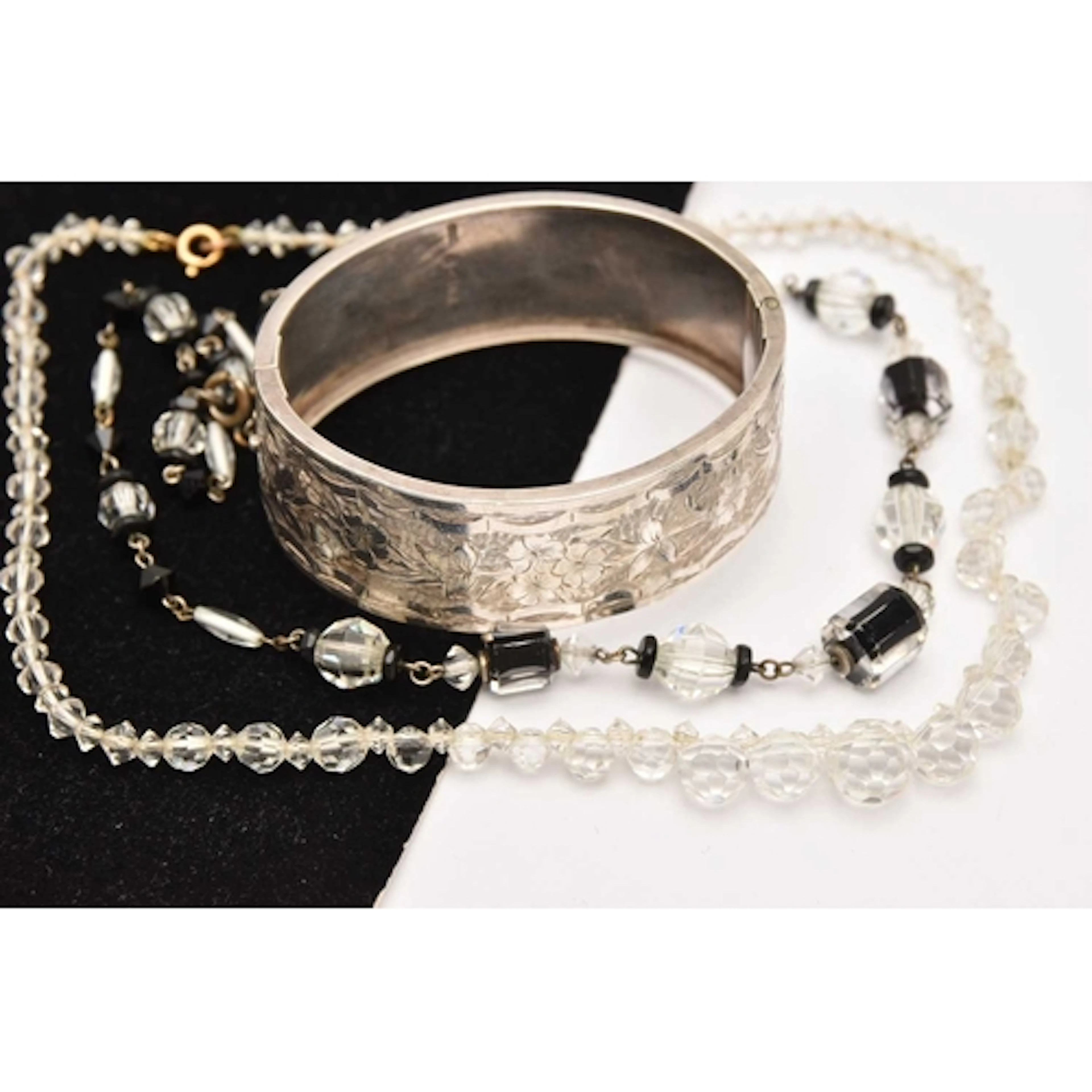 A SILVER HINGED BANGLE AND TWO BEADED NECKLACES, the wide hi...