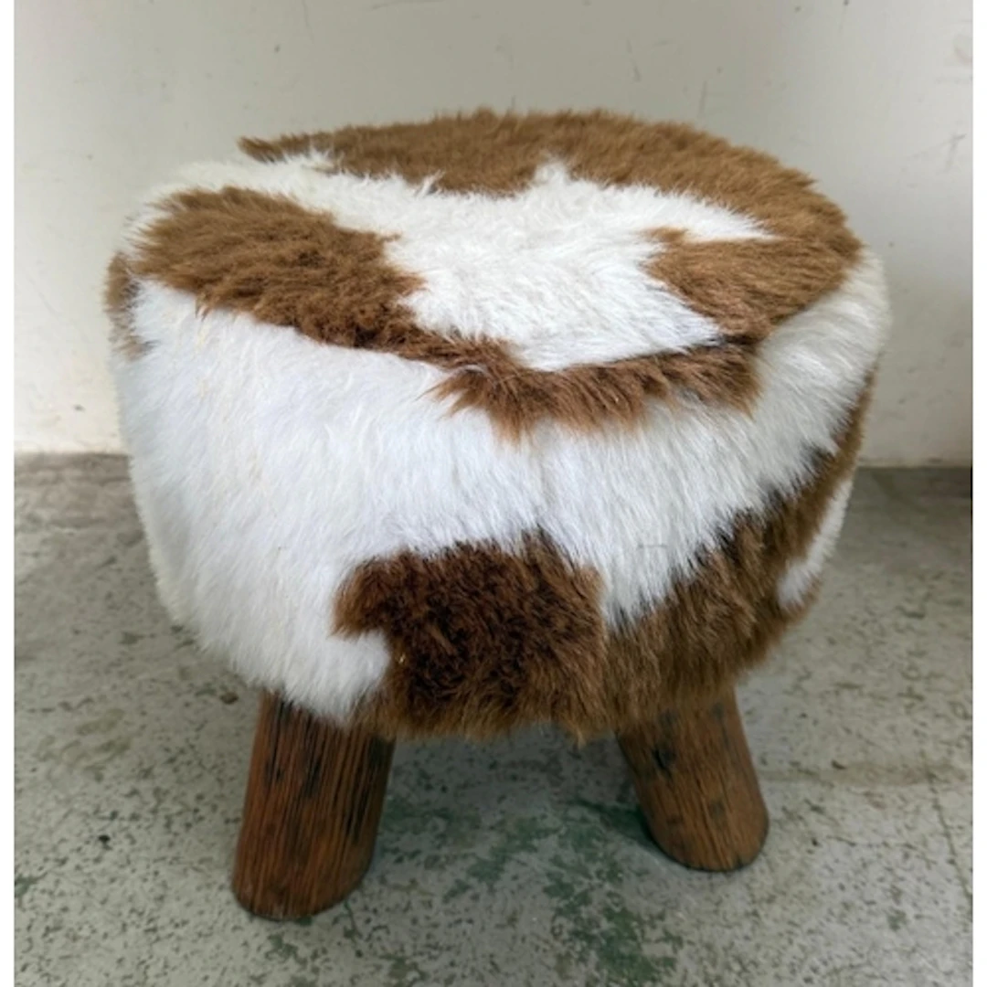 A cow hide effect stool on pine tripod legs.