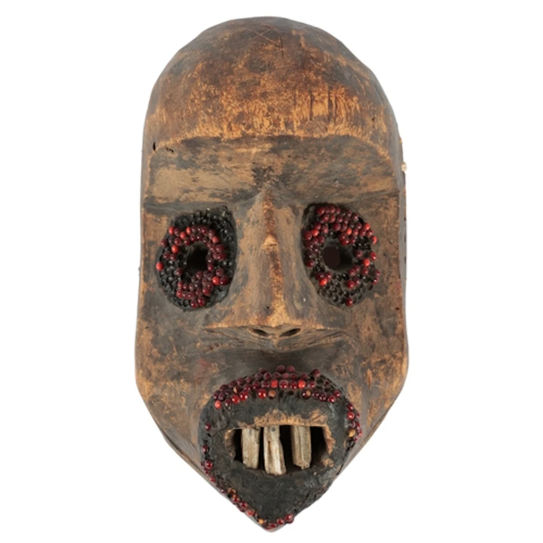 A Dan wood mask, Ivory Coast, set with seeds and animal bone...