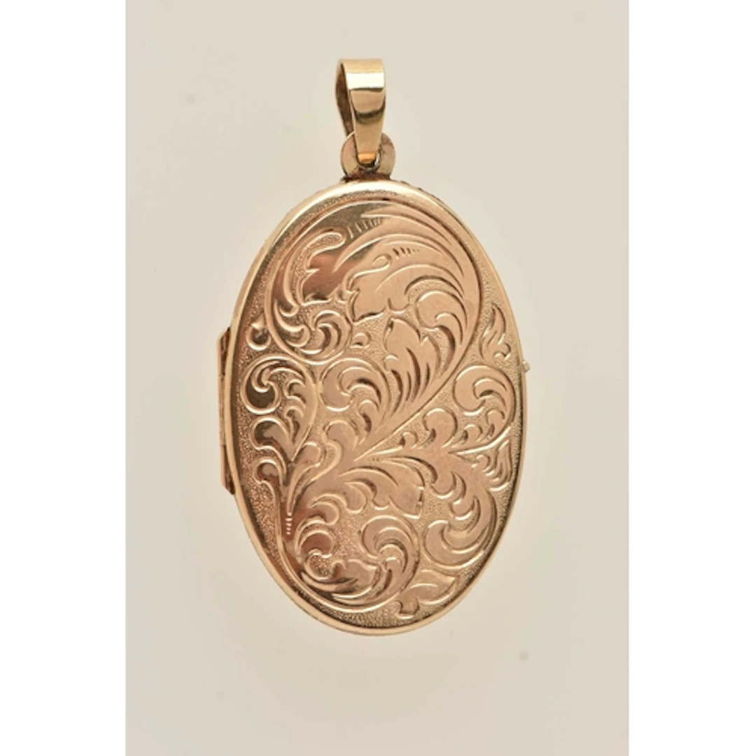 A YELLOW METAL LOCKET, an oval form locket with embossed fol...