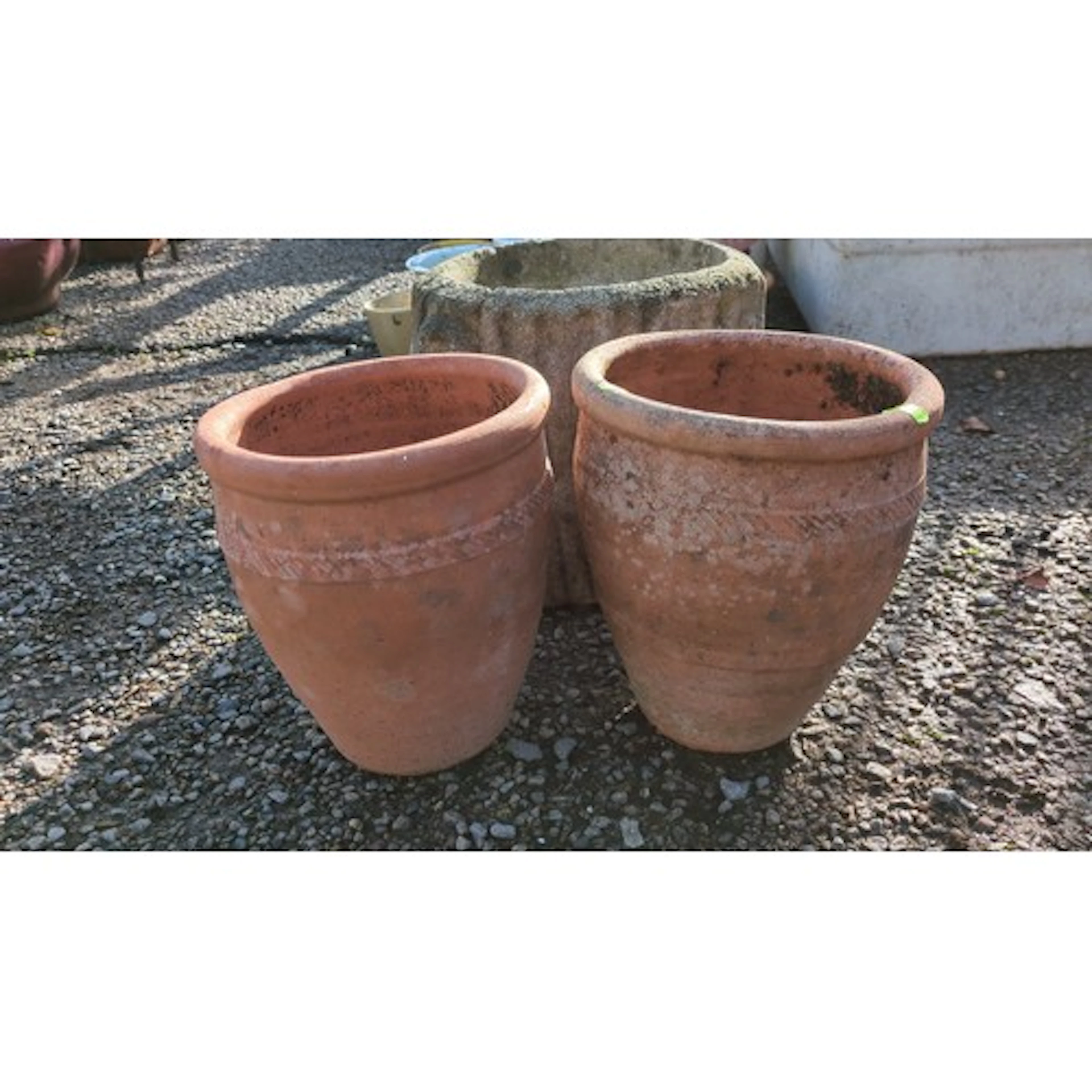 A pair of terracotta garden planters, each with incised band...