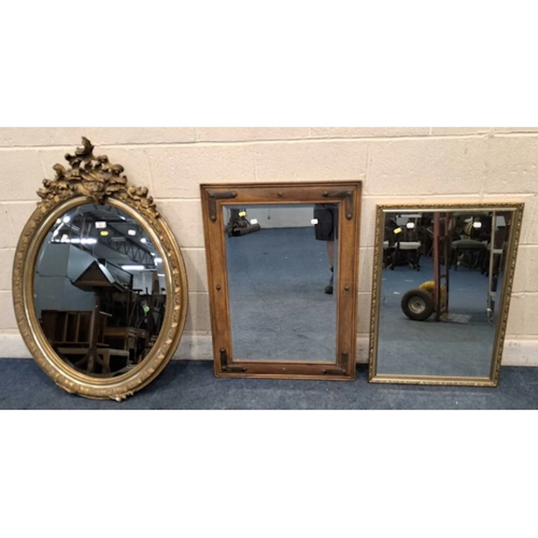 A GILT RESIN OVAL BEVELLED EDGE WALL MIRROR, with scrolled a...