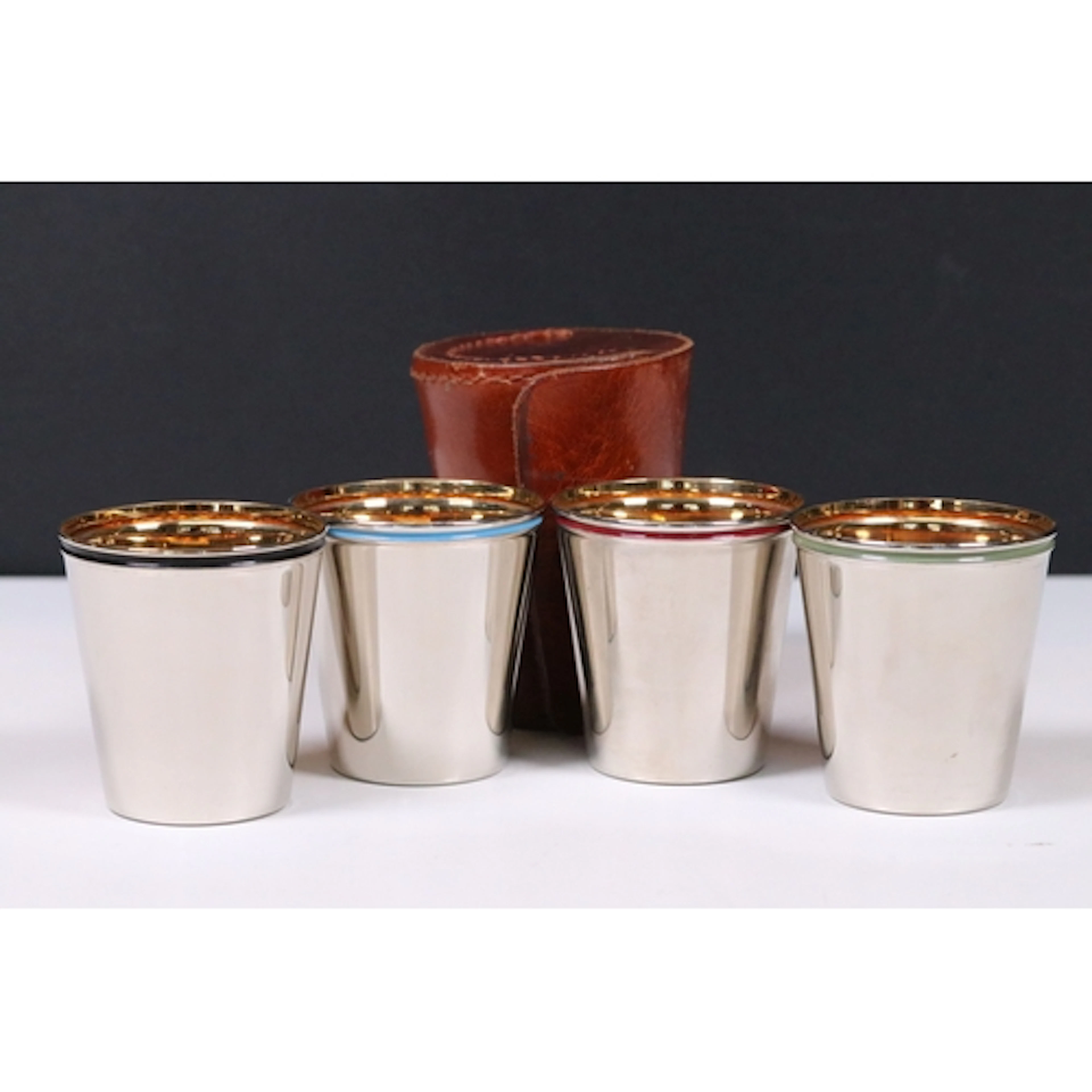 Set of four chrome stirrup cups with gilt interiors and diff...