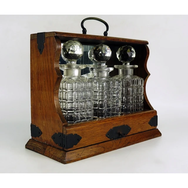 An oak and metal bound Tantalus containing three clear glass...