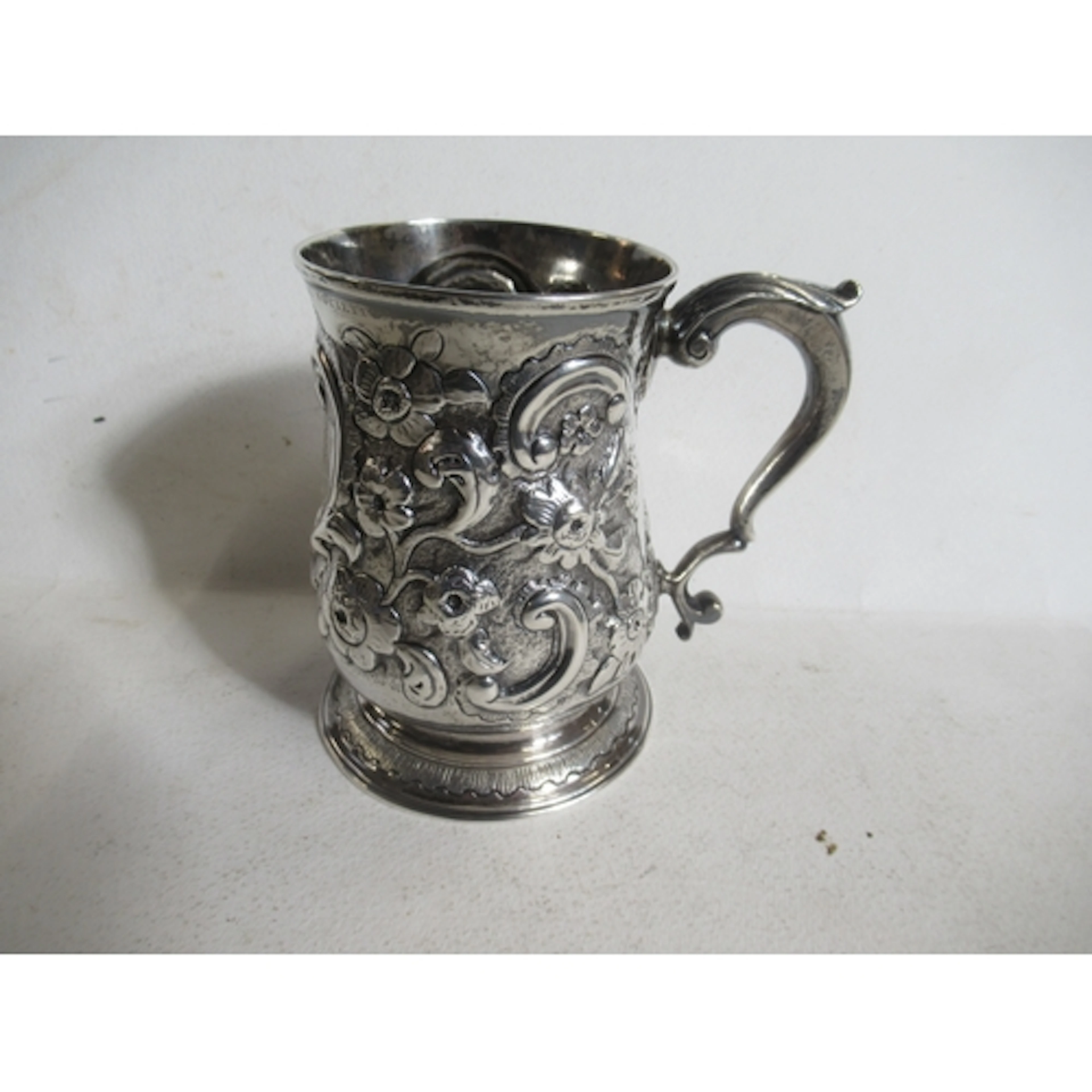 A Georgian silver tankard, with embossed floral decoration a...