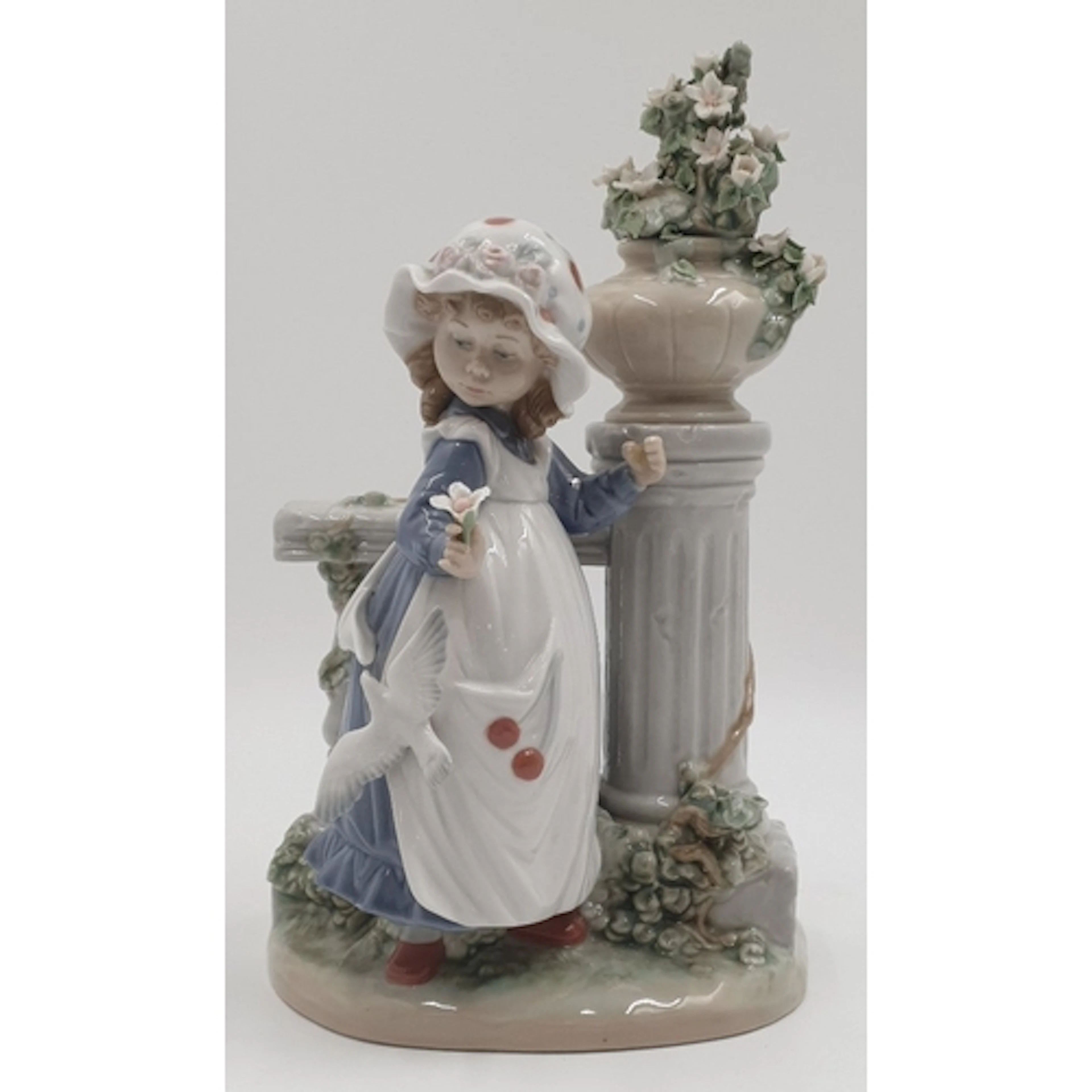 A Lladró porcelain figure group, girl with flowers beside an...