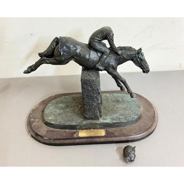 A sculpture of a steeplechase horse jumping a fence. In need...