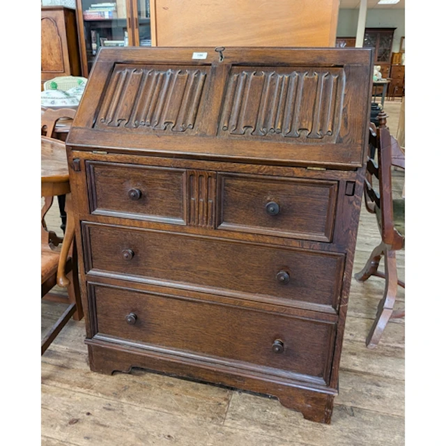 A reproduction oak linen fold panel carved writing bureau