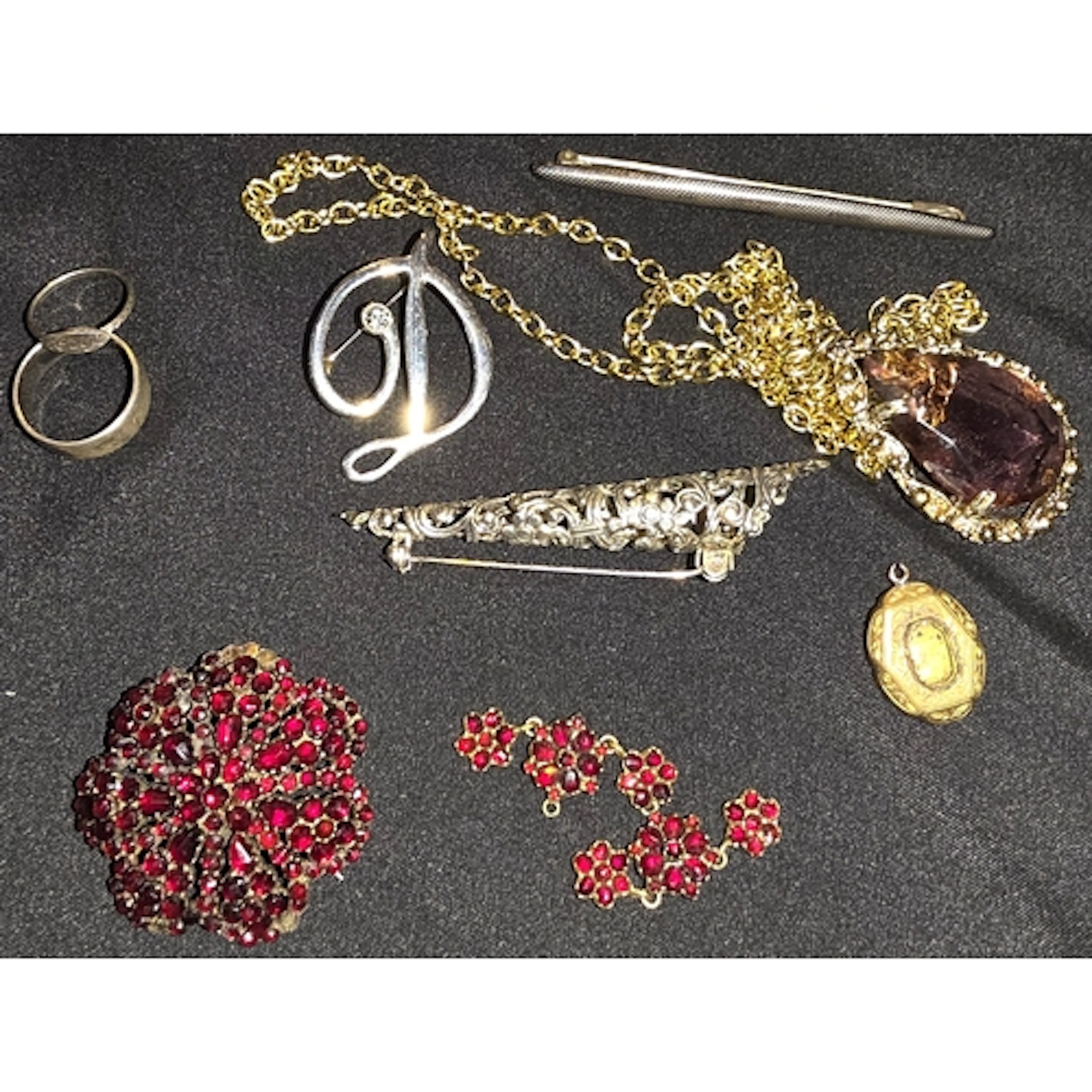A white metal brooch with red stones, a white metal baby rin...