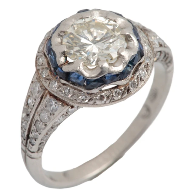 A sapphire and diamond ring, centring on a brilliant-cut dia...