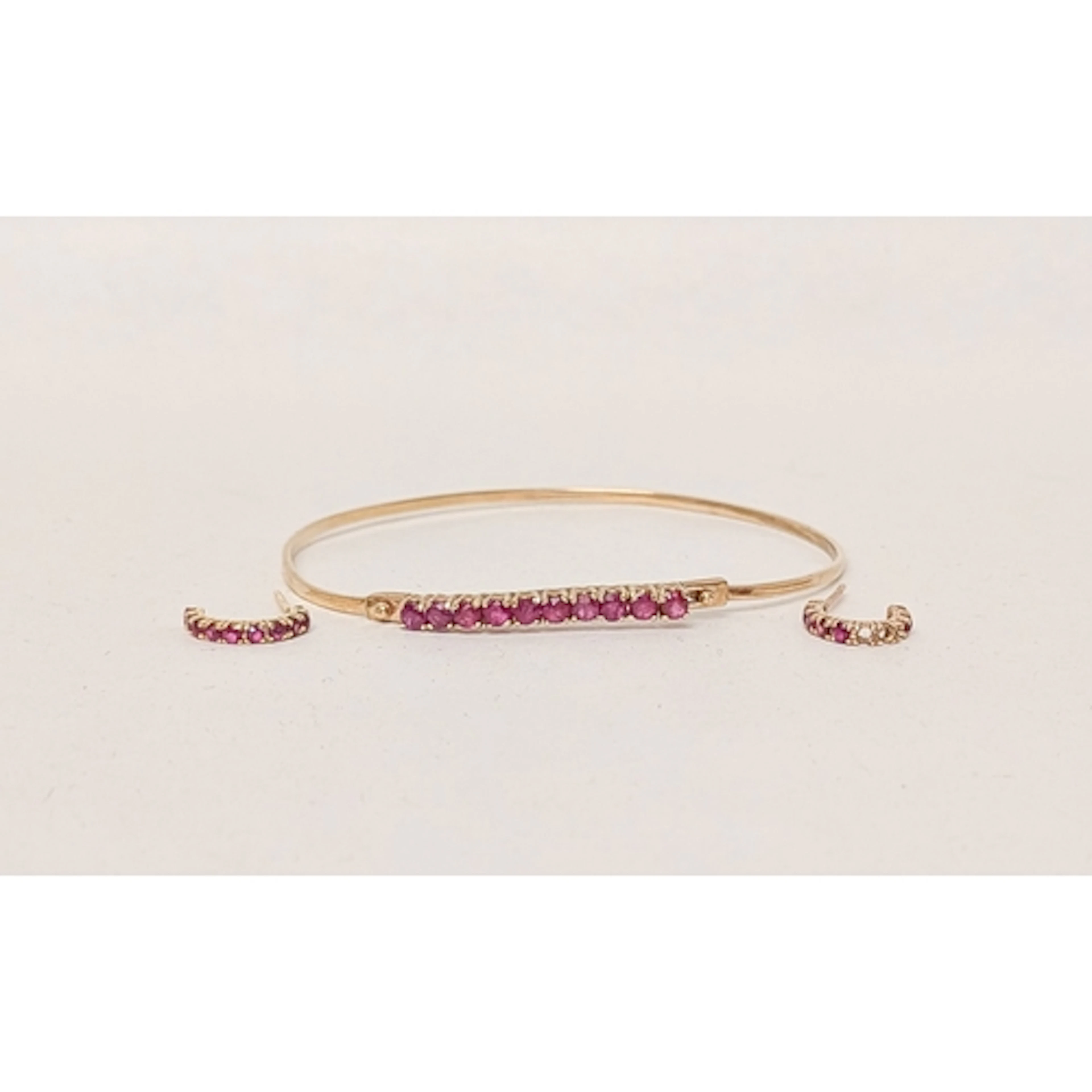 A 9ct gold fine bangle with a central ruby panel, and a pair...