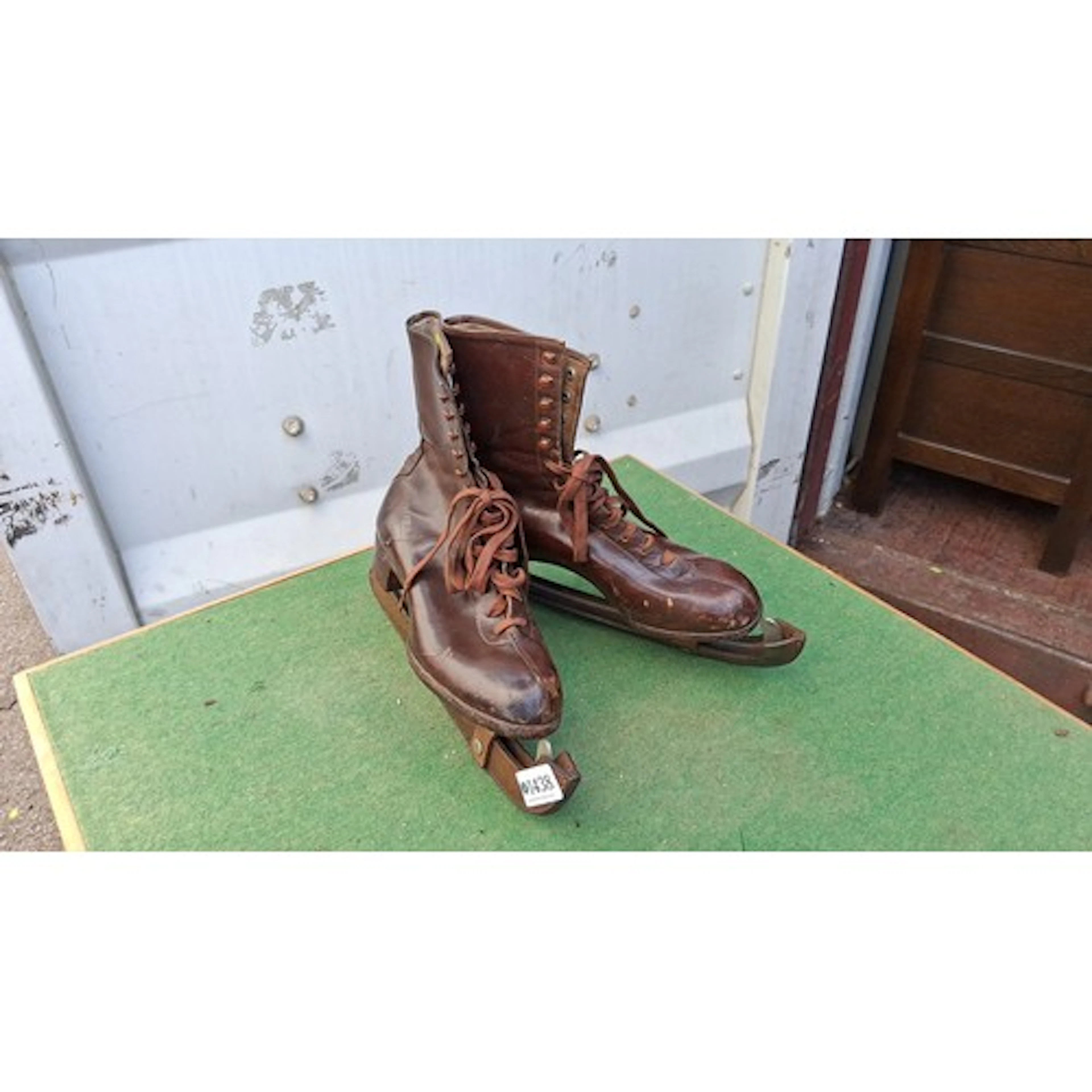 A pair of brown leather lace-up figure skates with steel bla...