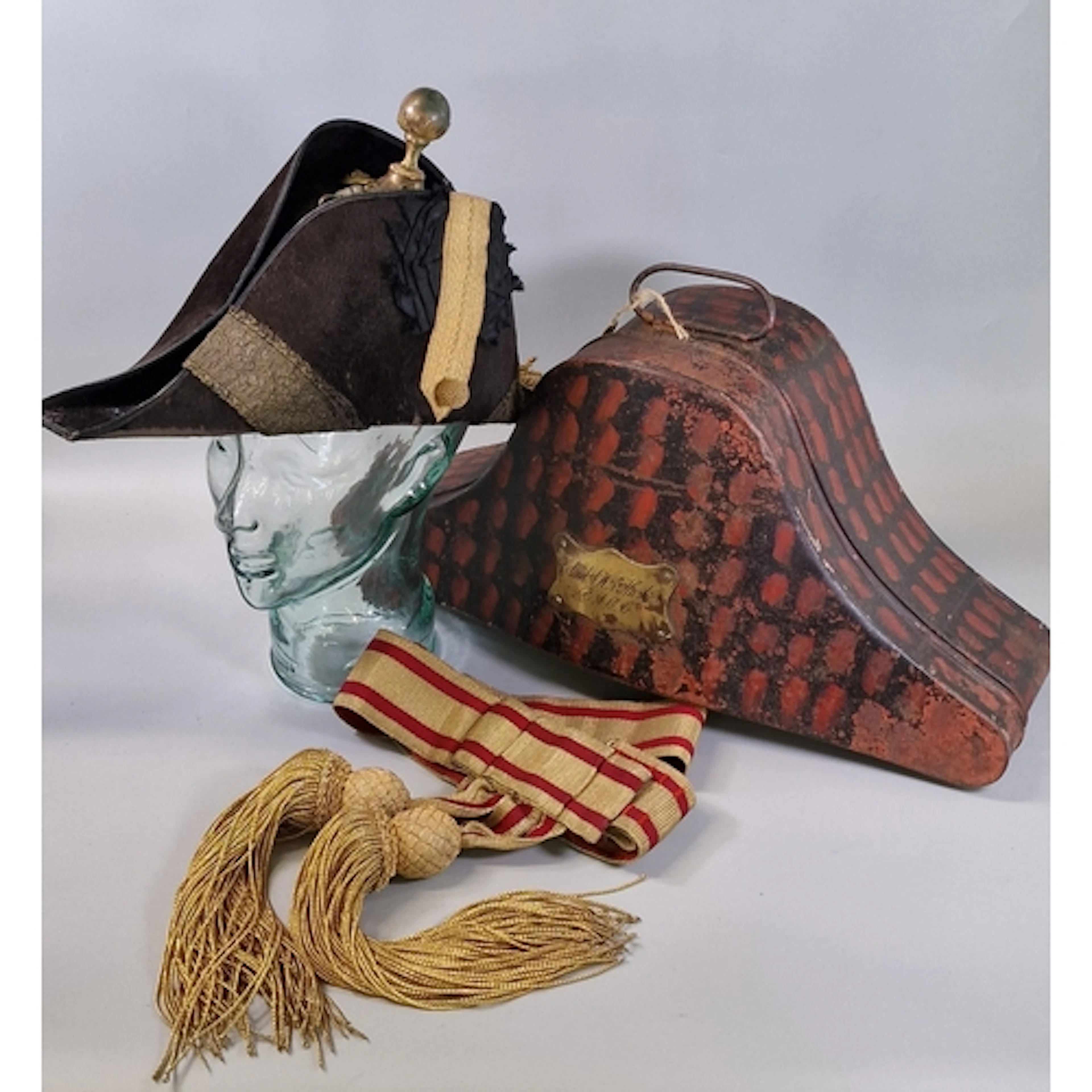 Bicorn hat, sash/belt and carrying tin associated with Colon...