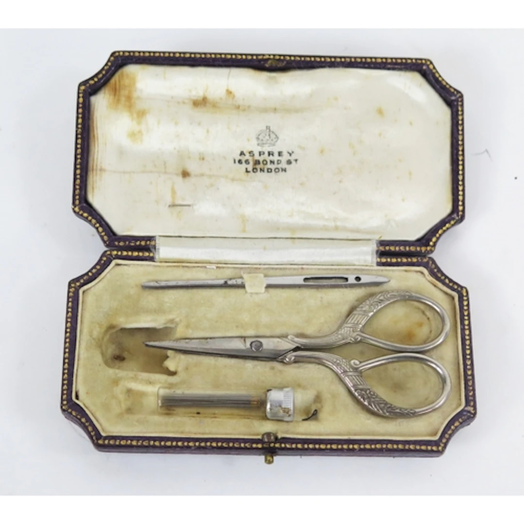 An early 20th century sewing kit containing scissors, needle...