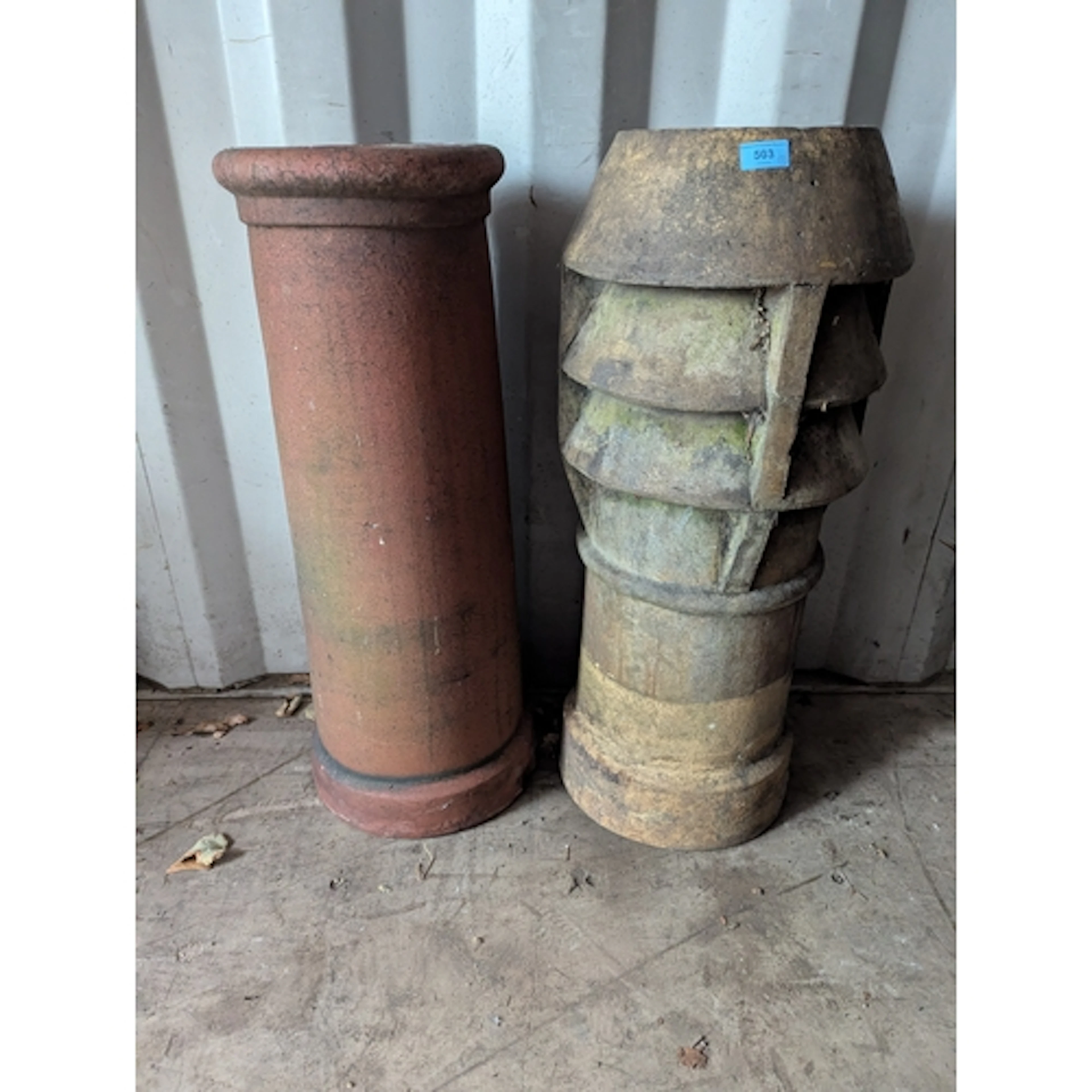 Two weathered terracotta chimney pots to include a cylindric...