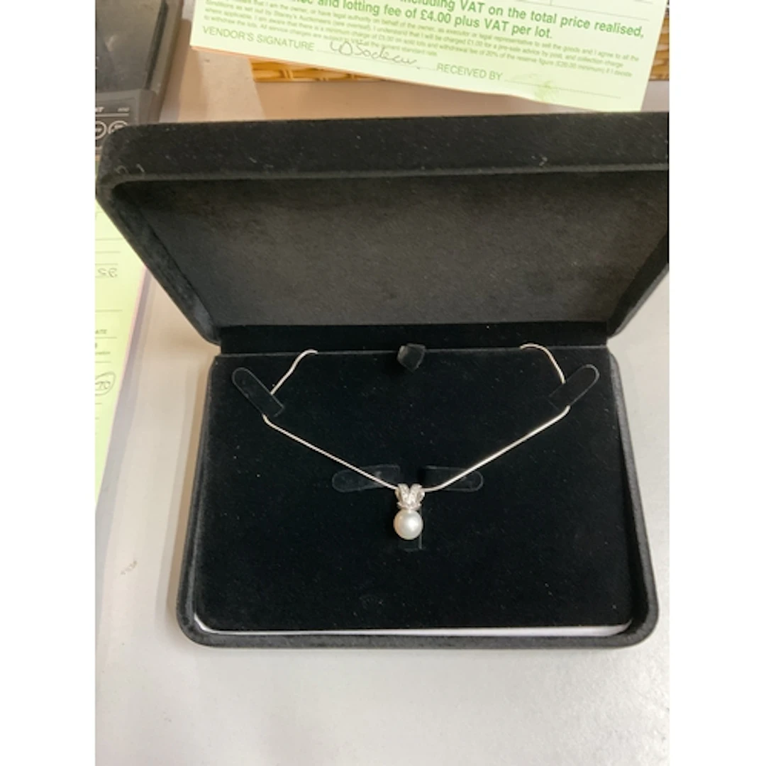 18 ct diamond set bow with a large south sea pearl suspended...