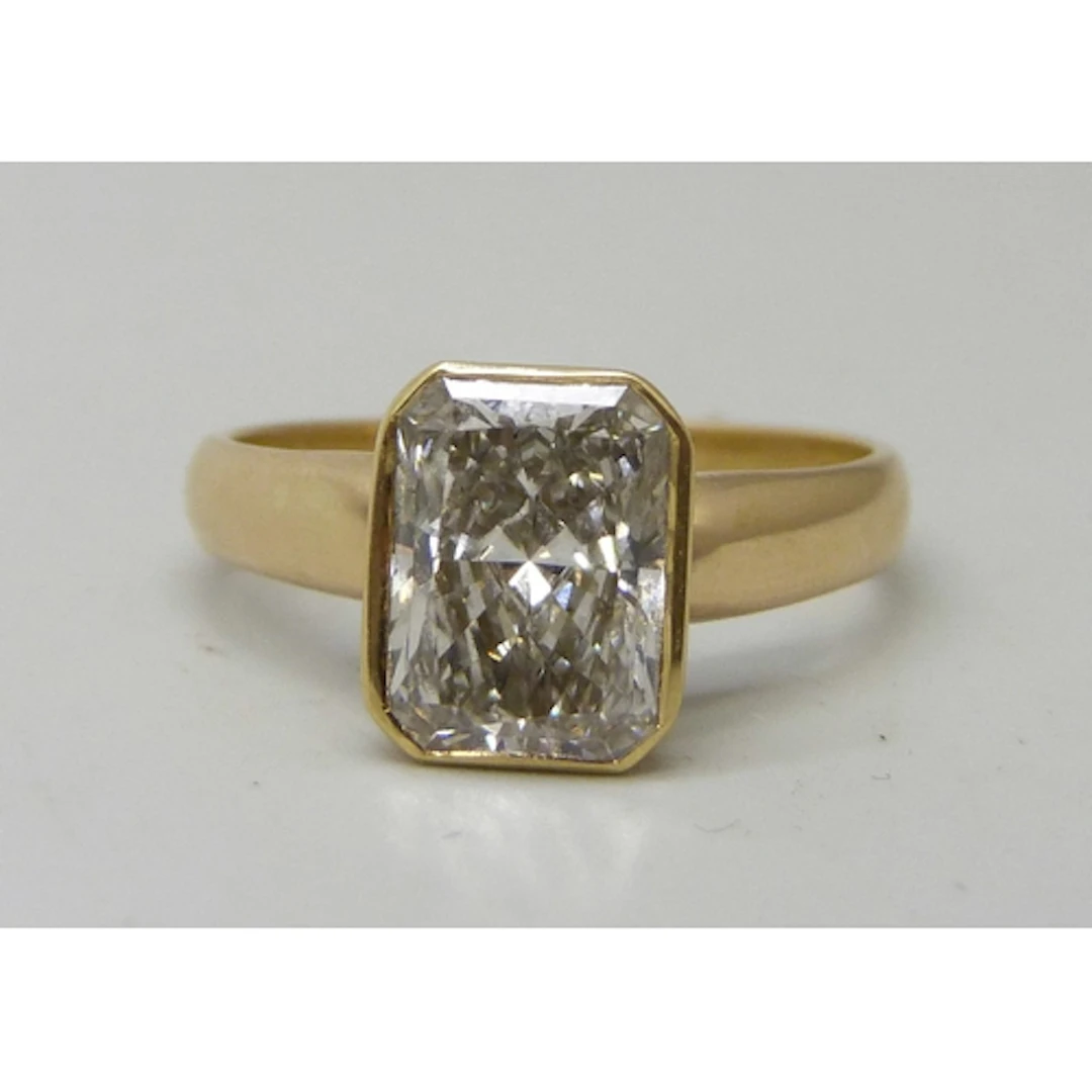 An 18ct gold radiant rectangular cut diamond solitaire ring,...