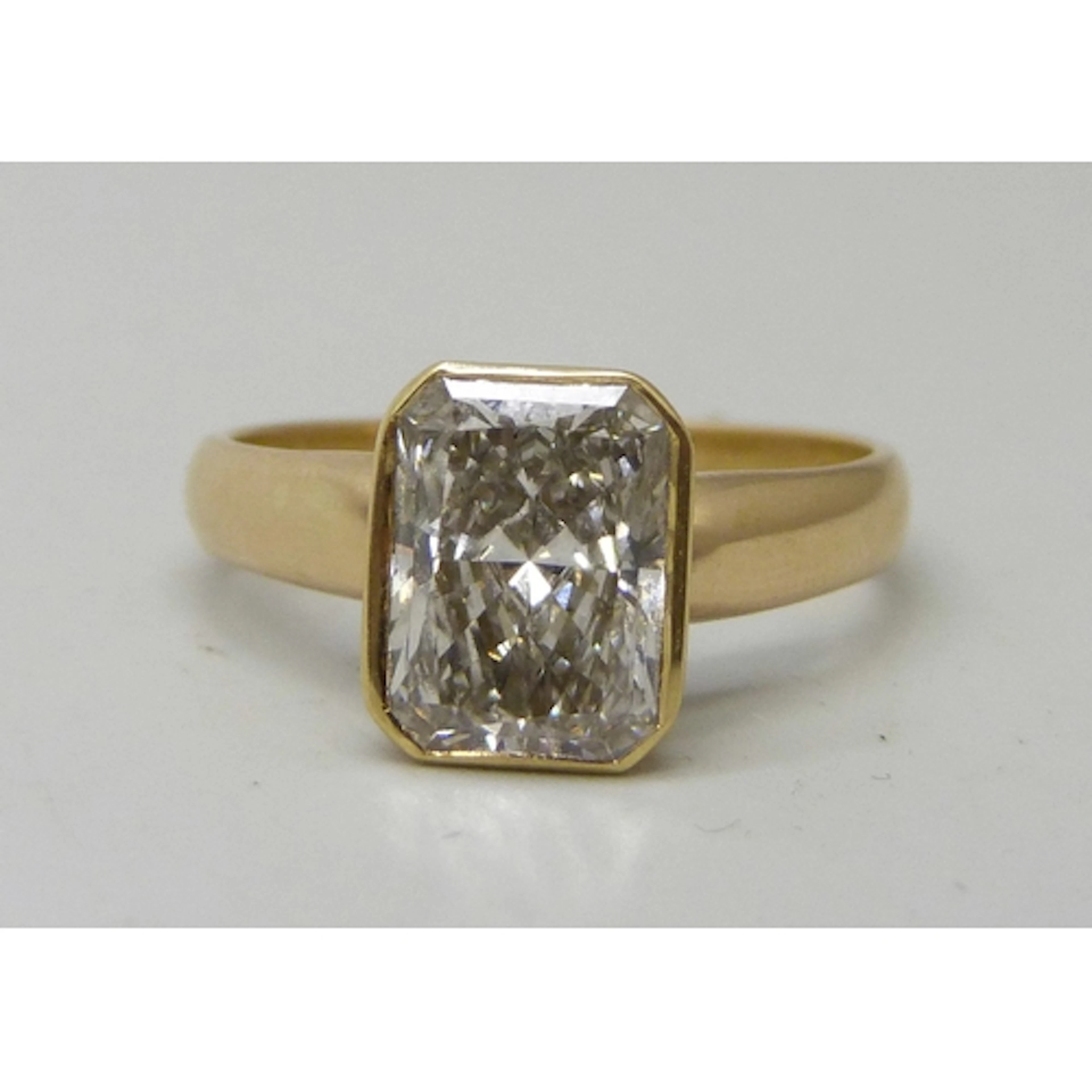 An 18ct gold radiant rectangular cut diamond solitaire ring,...