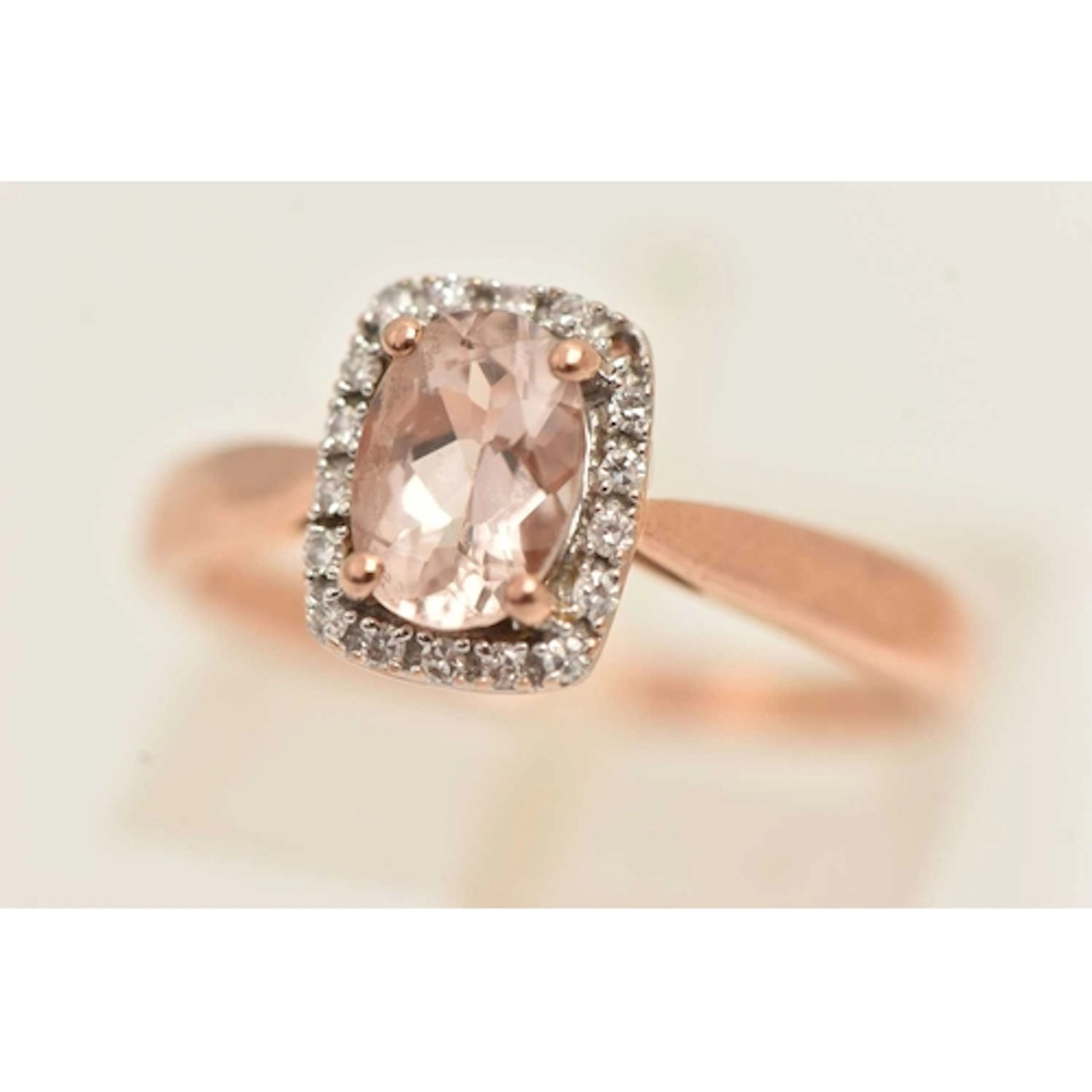 A 9CT ROSE GOLD GEM SET RING, an oval cut morganite, set wit...