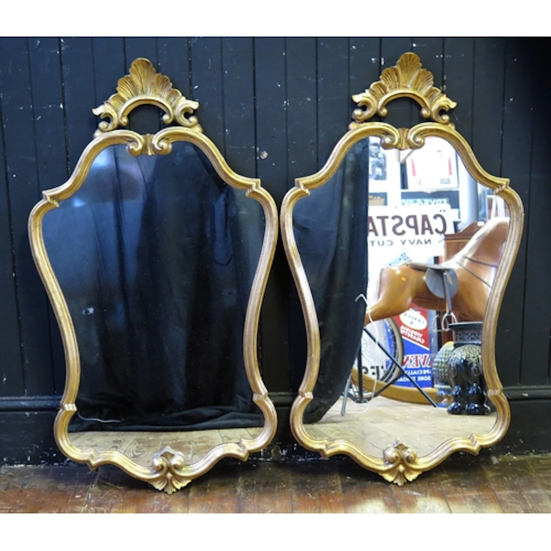 A pair of gilt framed wall mirrors of cartouche-shaped outli...
