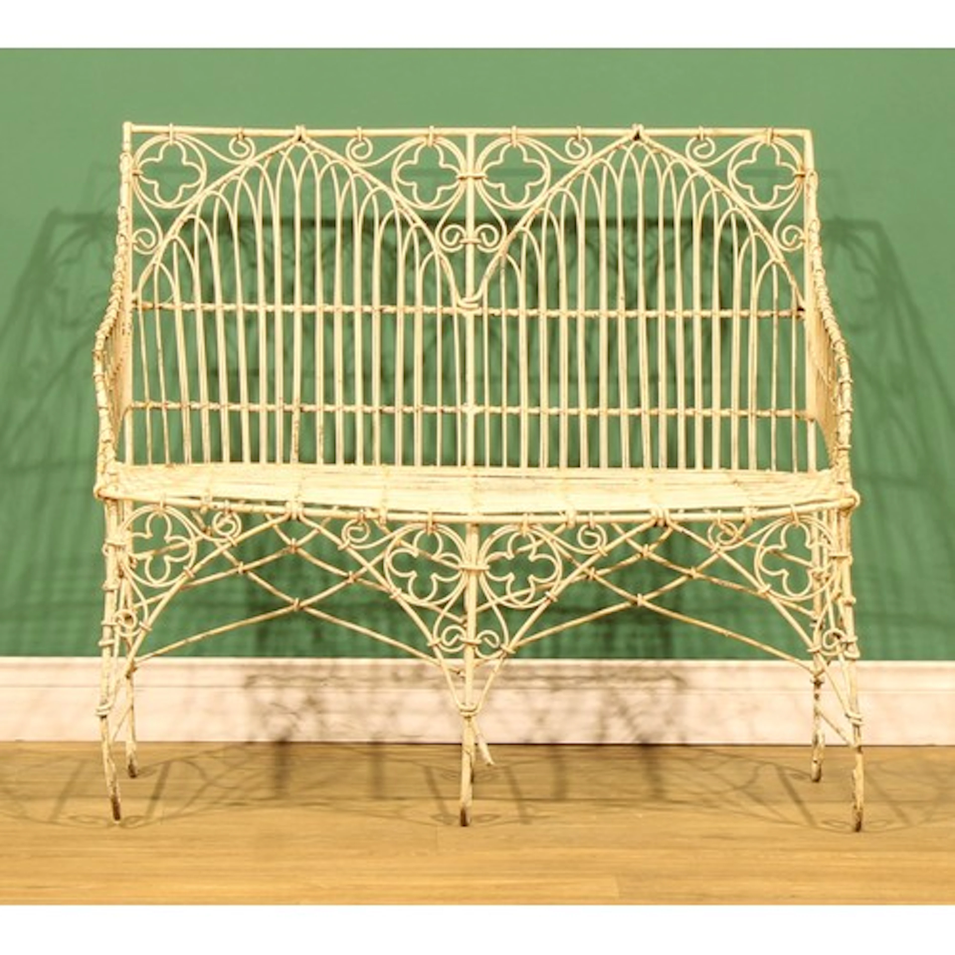 A wrought iron and wirework garden bench, in the Gothic Revi...