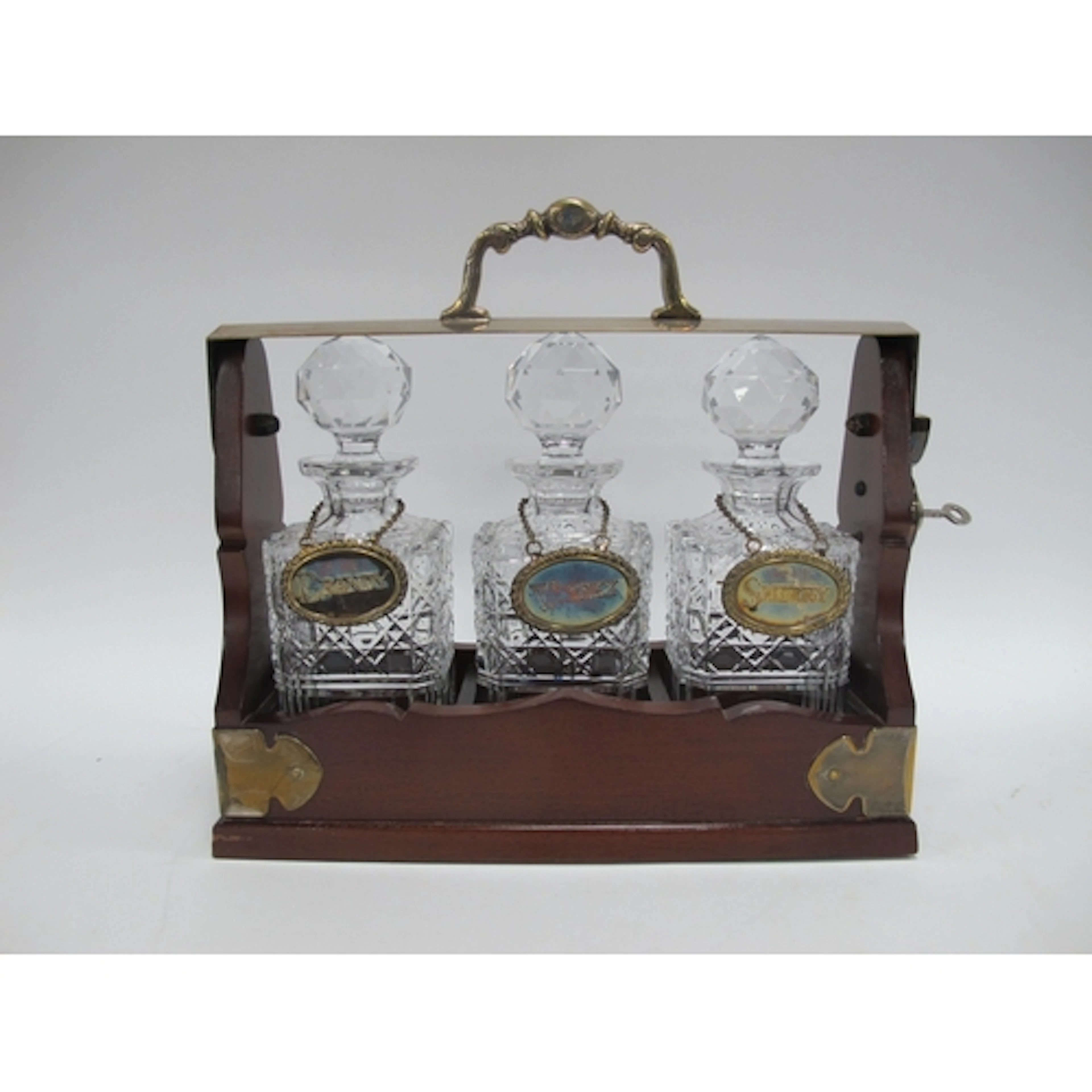 A vintage brass-mounted mahogany three-decanter tantalus, co...