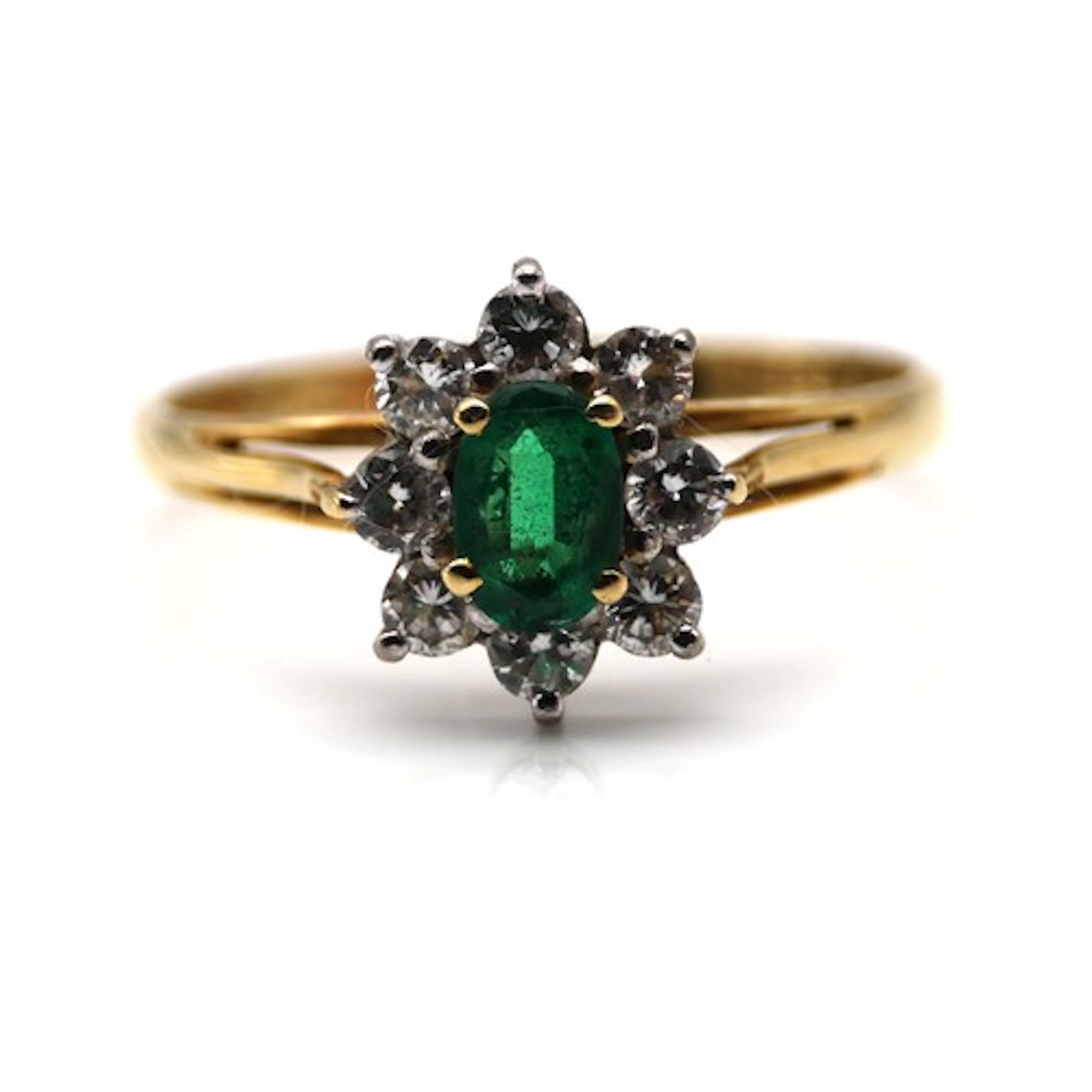 A modern emerald and diamond cluster ring, centred with an o...