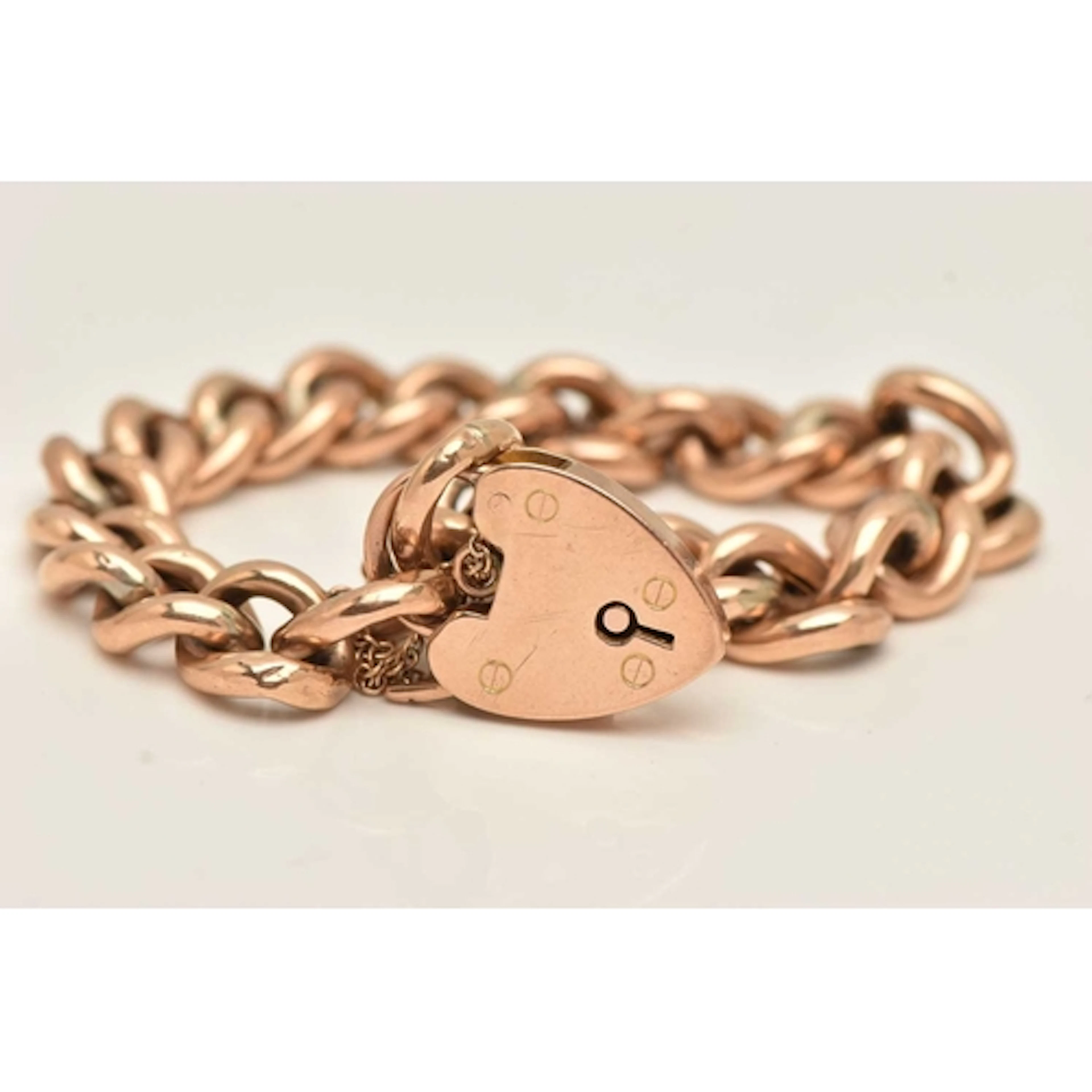 A YELLOW METAL CURB LINK BRACELET, hollow curb links, fitted...