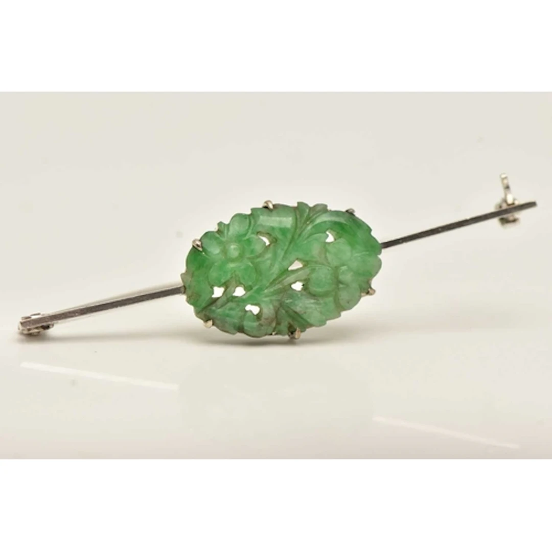 A WHITE METAL CARVED JADE BROOCH, the carved jade of a flora...