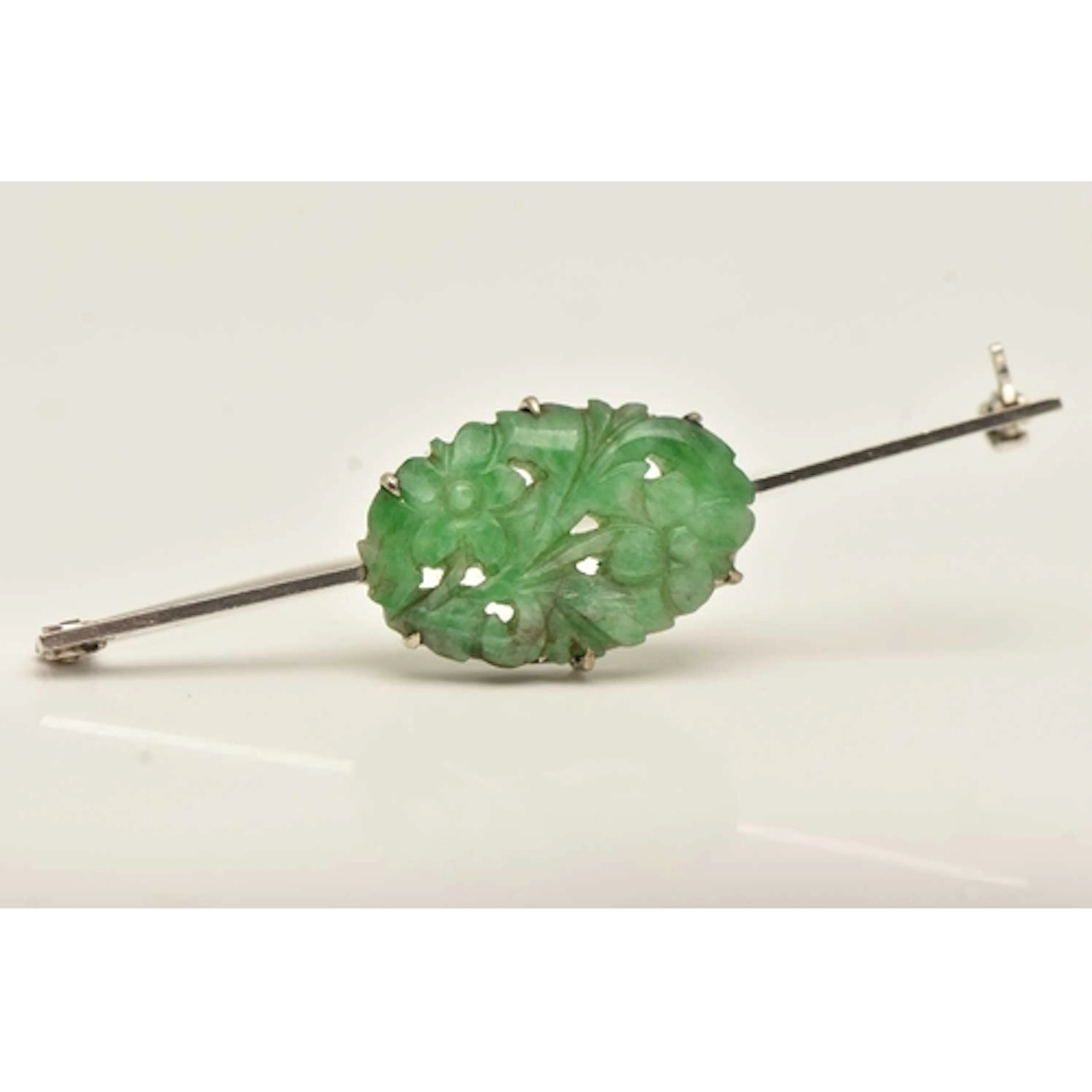 A WHITE METAL CARVED JADE BROOCH, the carved jade of a flora...