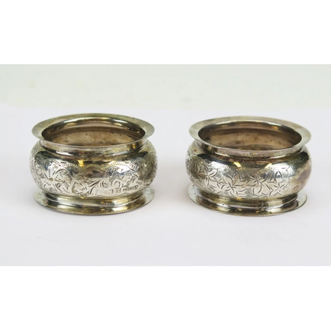 An Edward VII pair of silver napkin rings with chased foliat...