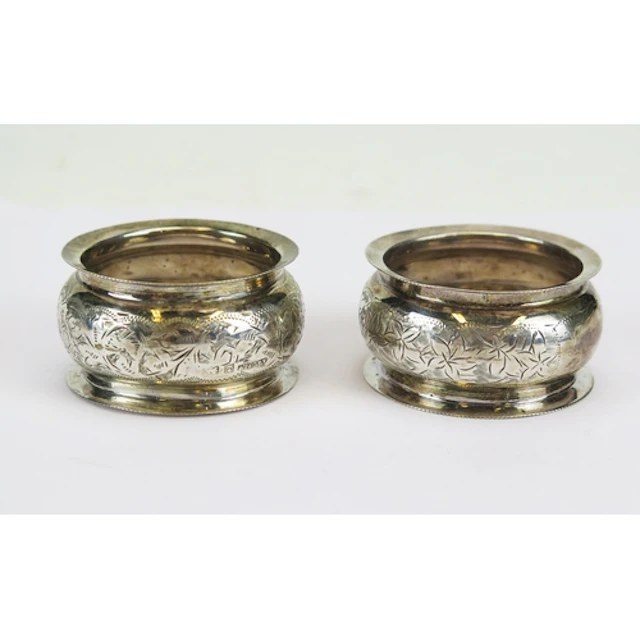 An Edward VII pair of silver napkin rings with chased foliat...