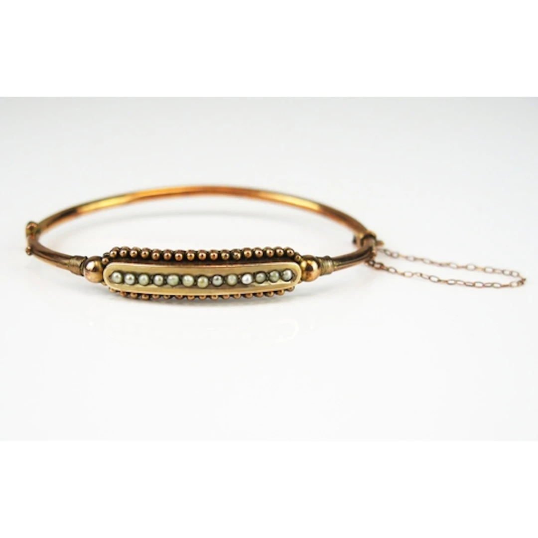 A Victorian 9ct rose gold hinged bangle wet with a line of s...
