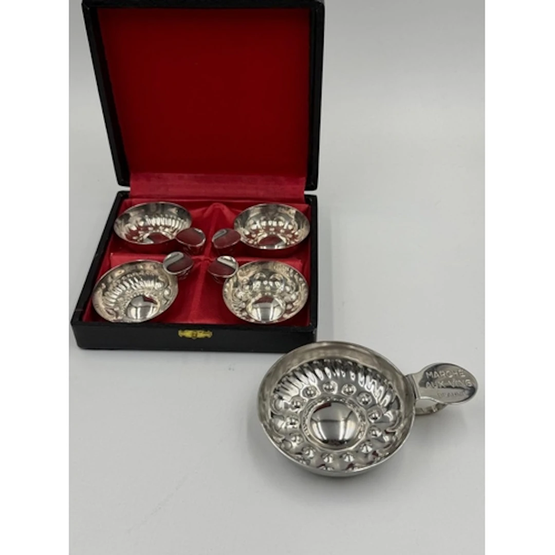 A boxed set of four white metal wine tasting cups and one la...