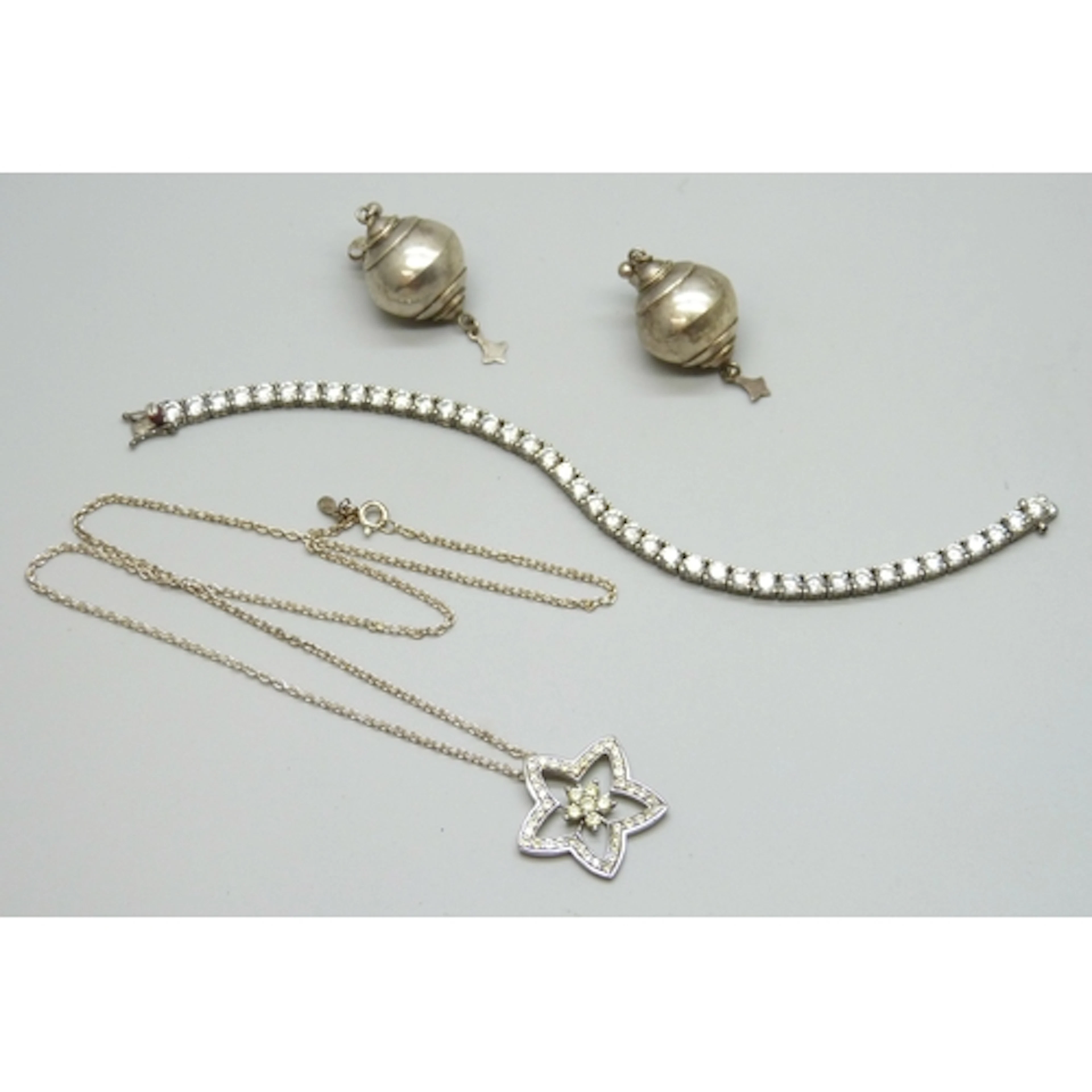 A silver tennis bracelet, a silver necklace, and a pair of w...