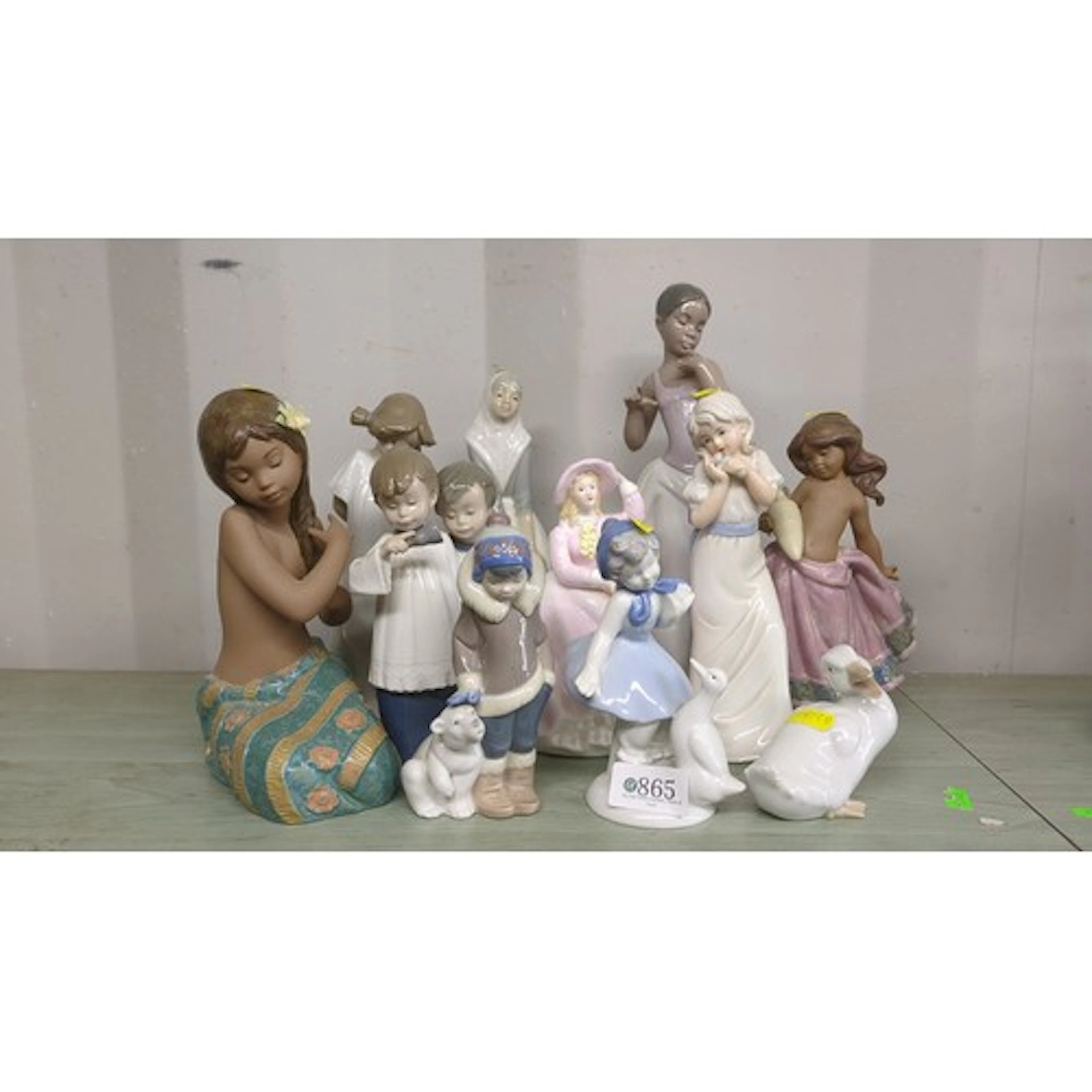 A quantity of glazed porcelain figurines, including Lladro e...
