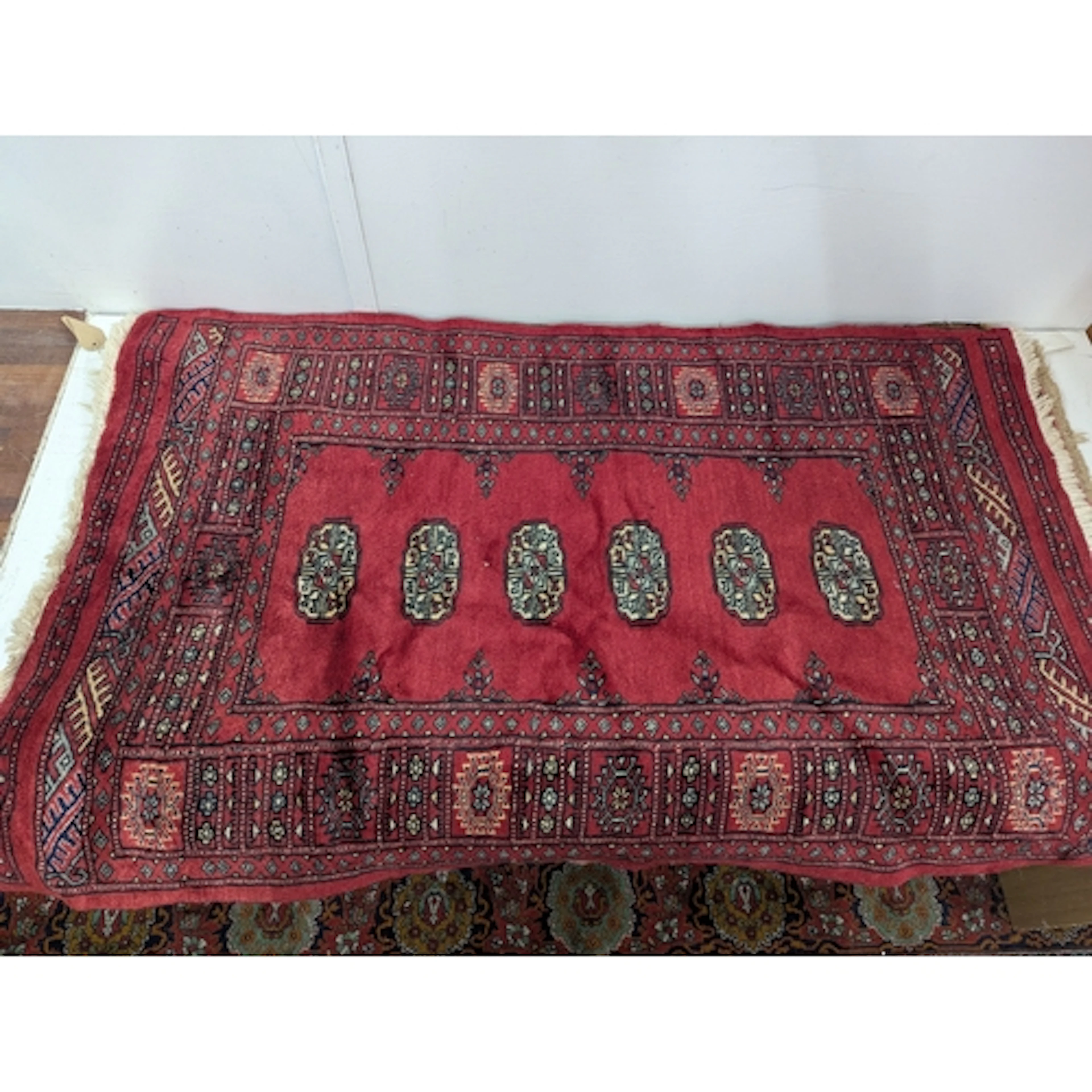 Three rugs to include a Bokhara style rug with six repeating...