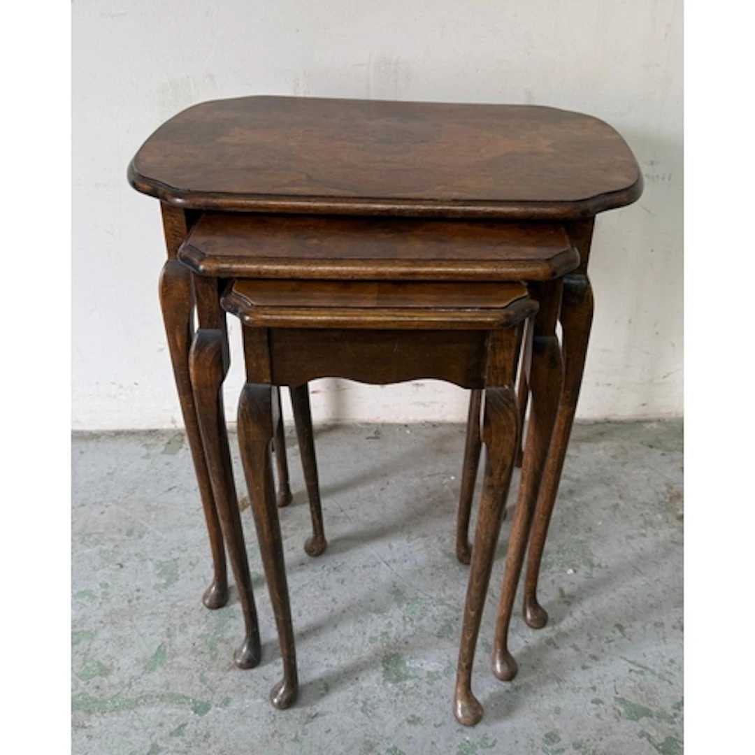 A nest of three burr walnut veneer side tables on cabriole l...