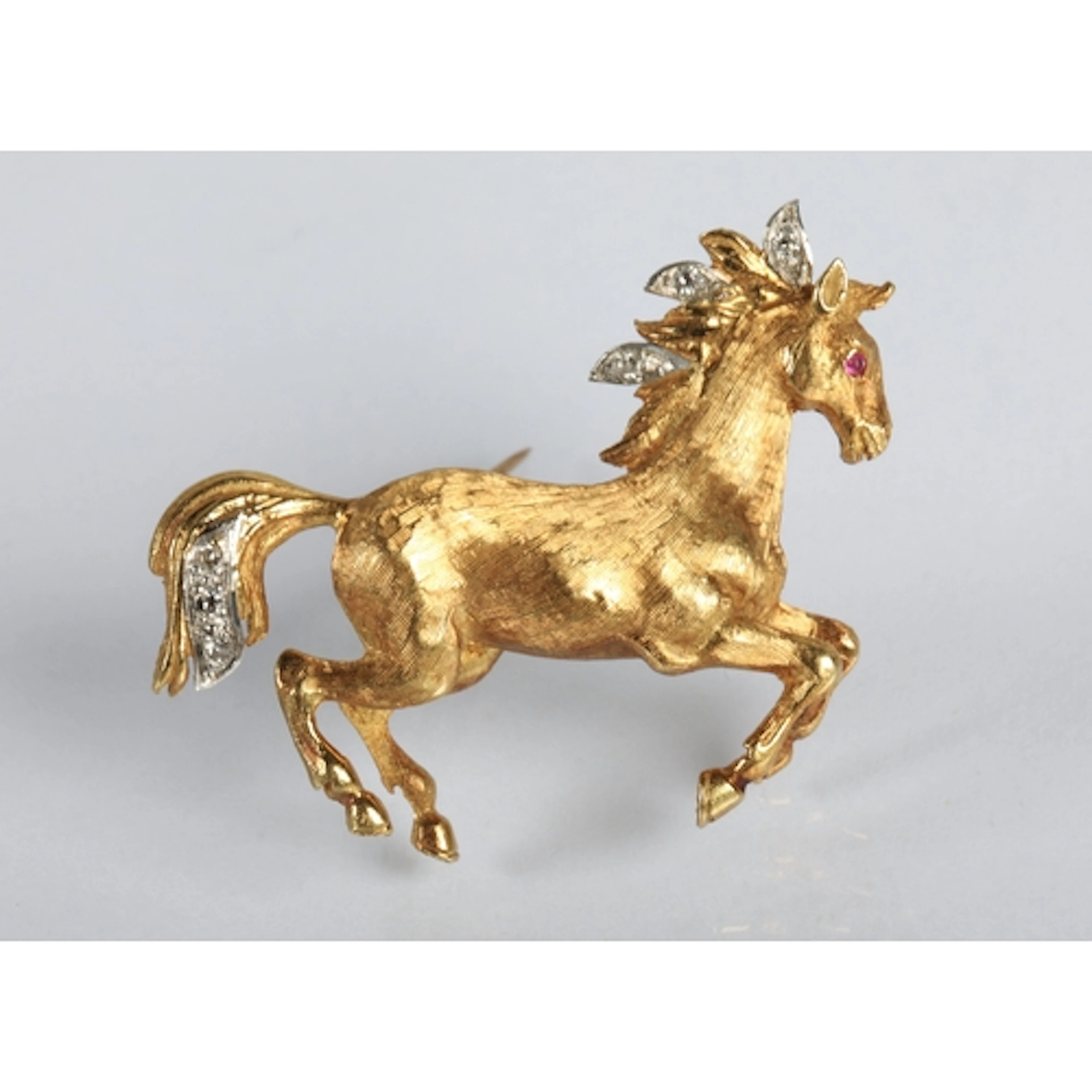 Unmarked yellow metal brooch in the form of a prancing horse...