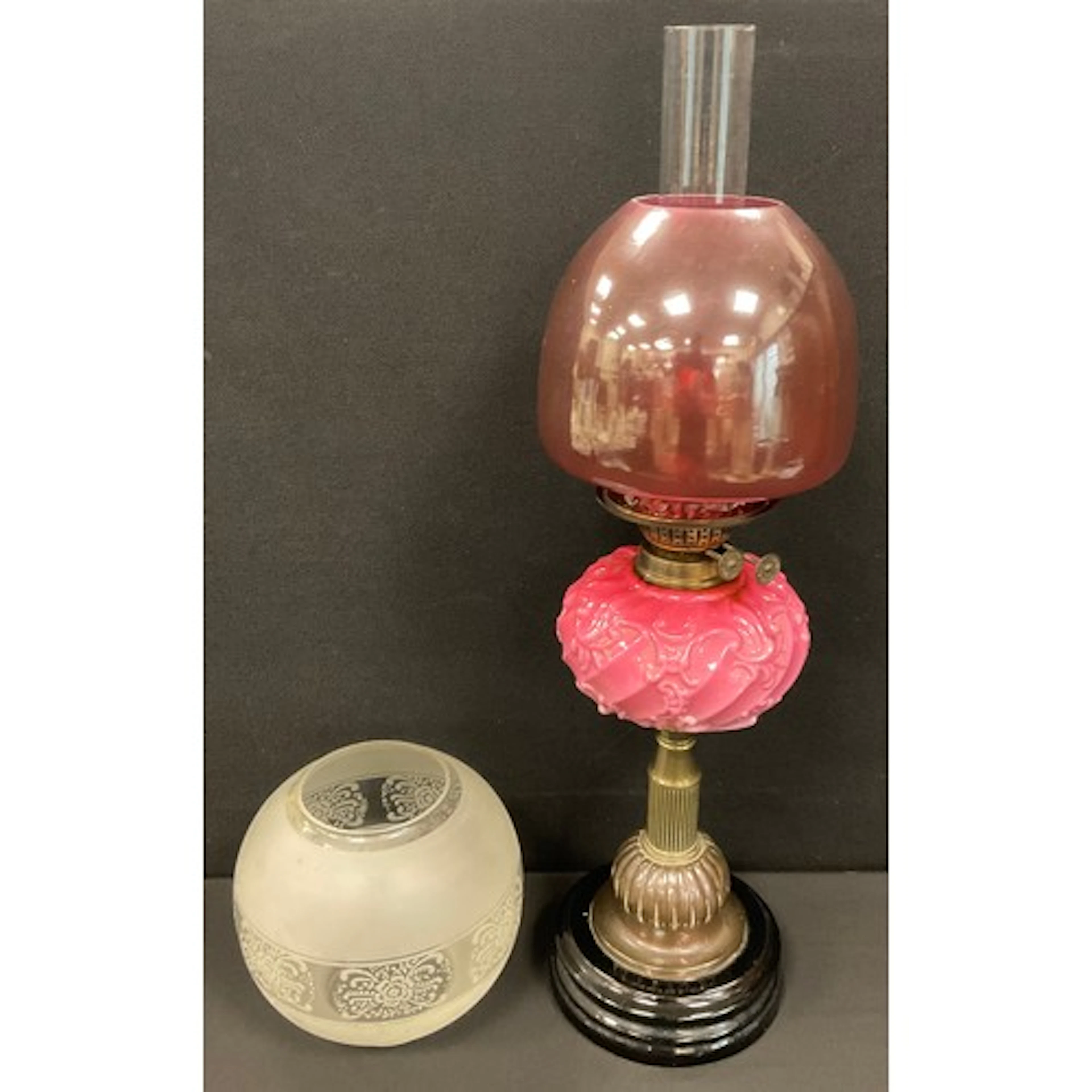 An early 20th century oil lamp, the pink reservoir moulded i...