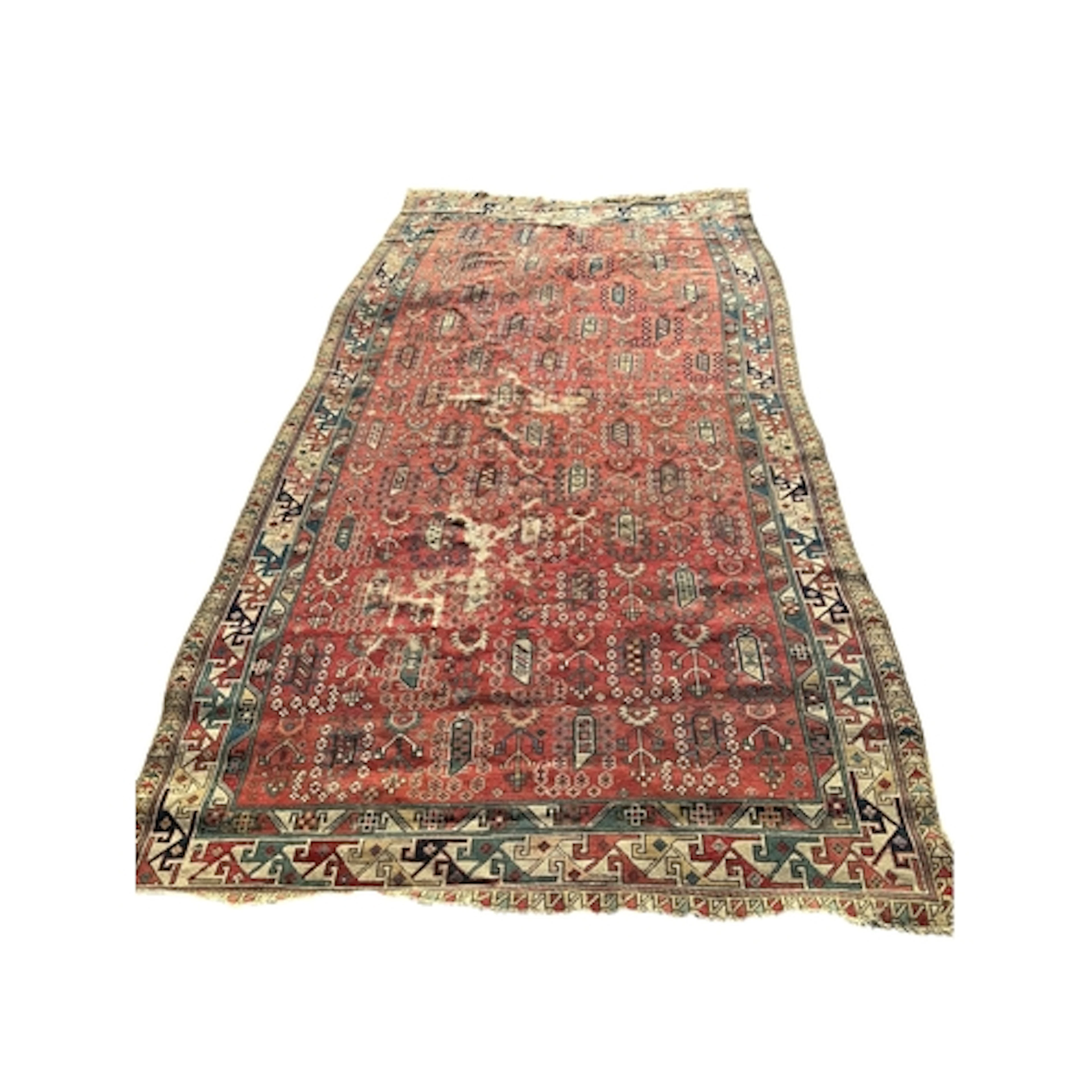 An antique Caucasian brick red ground hall carpet, (worn and...