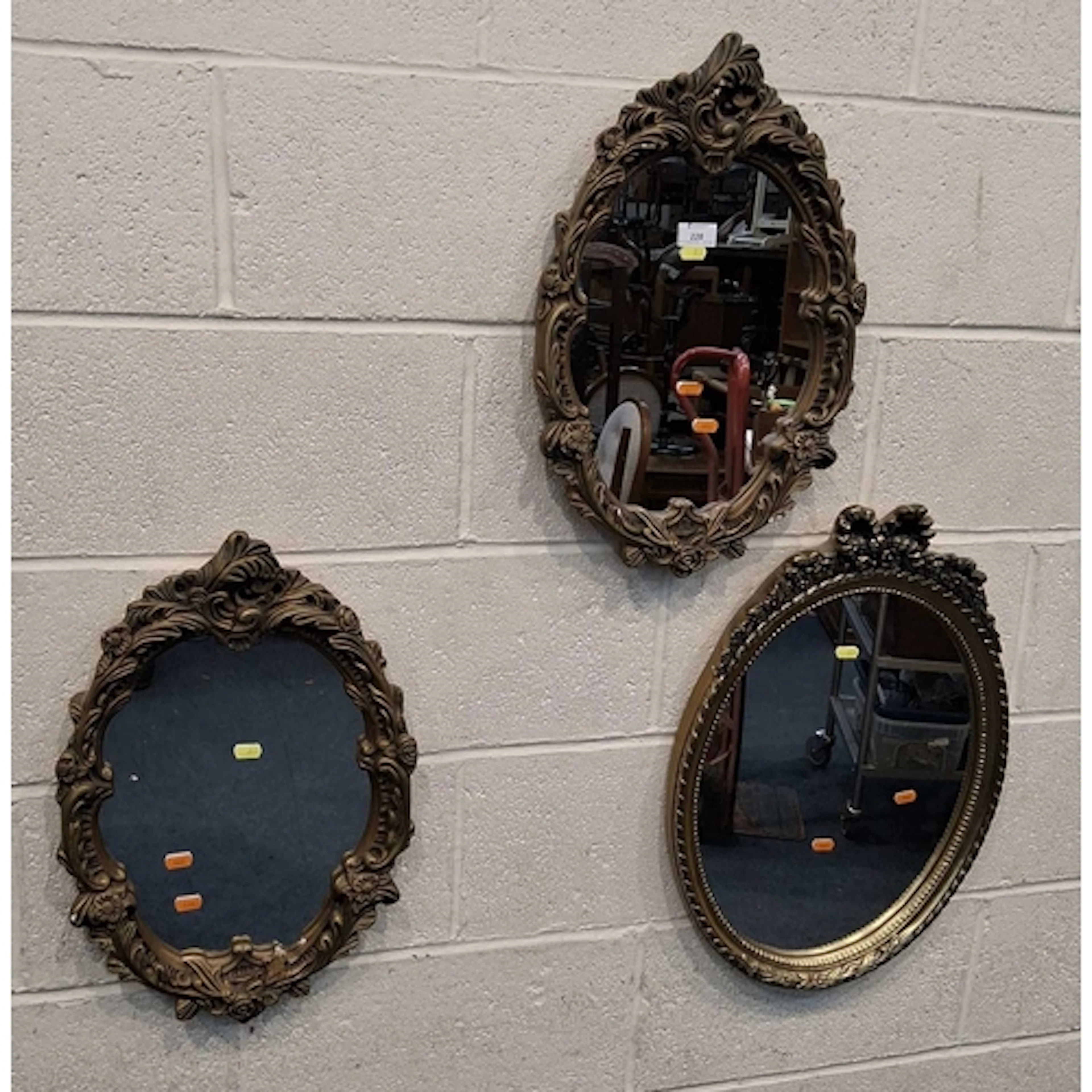 A PAIR OF GILT RESIN OVAL WALL MIRRORS, with a foliate frame...