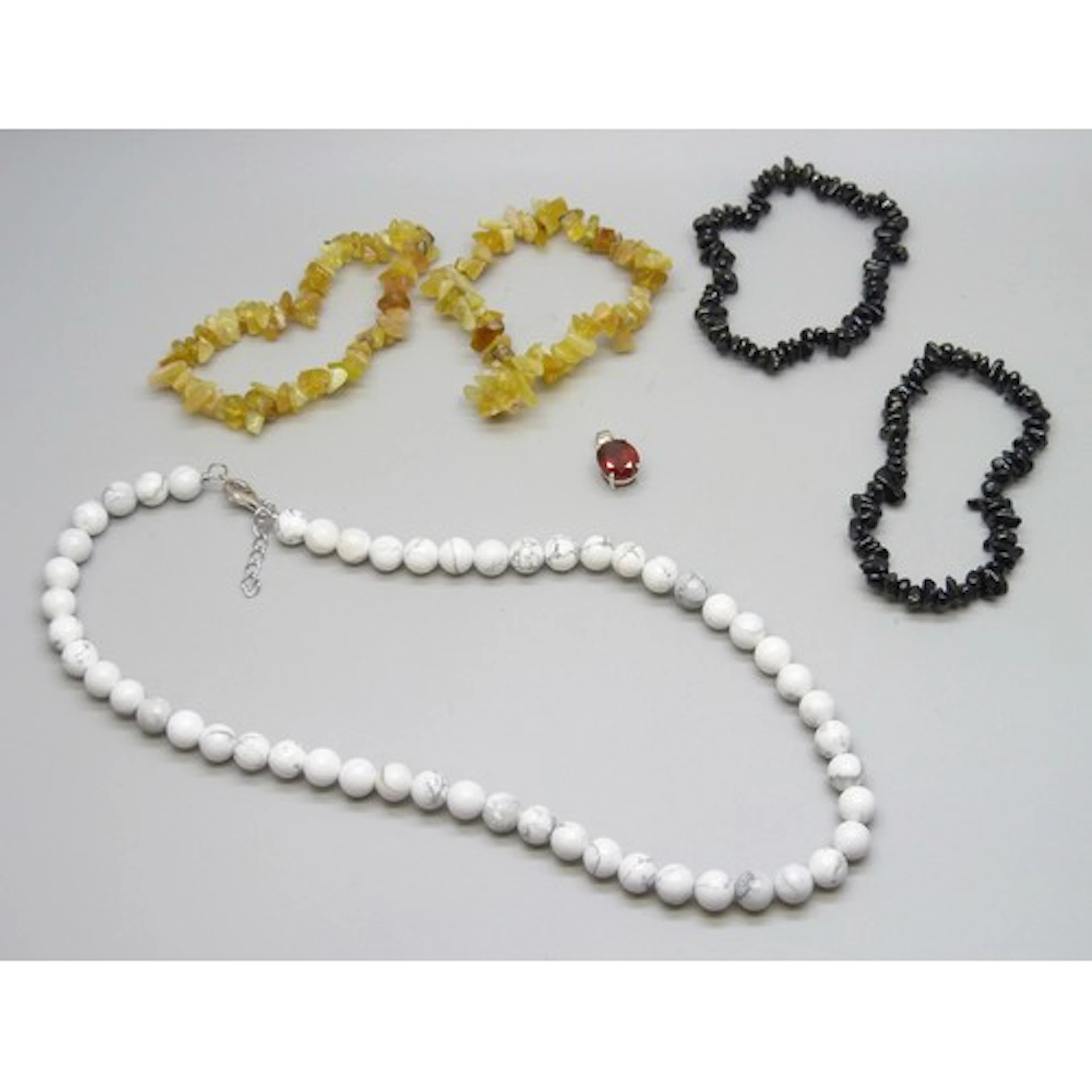 A collection of jewellery including a 243.7ct white howlite ...