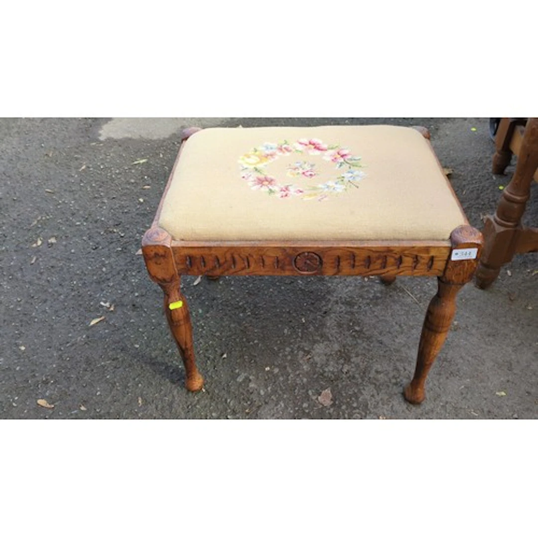 Rectangular carved wood footstool with a padded floral needl...