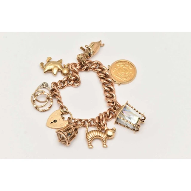 A 9CT YELLOW GOLD CHARM BRACELET, a graduated curb link brac...