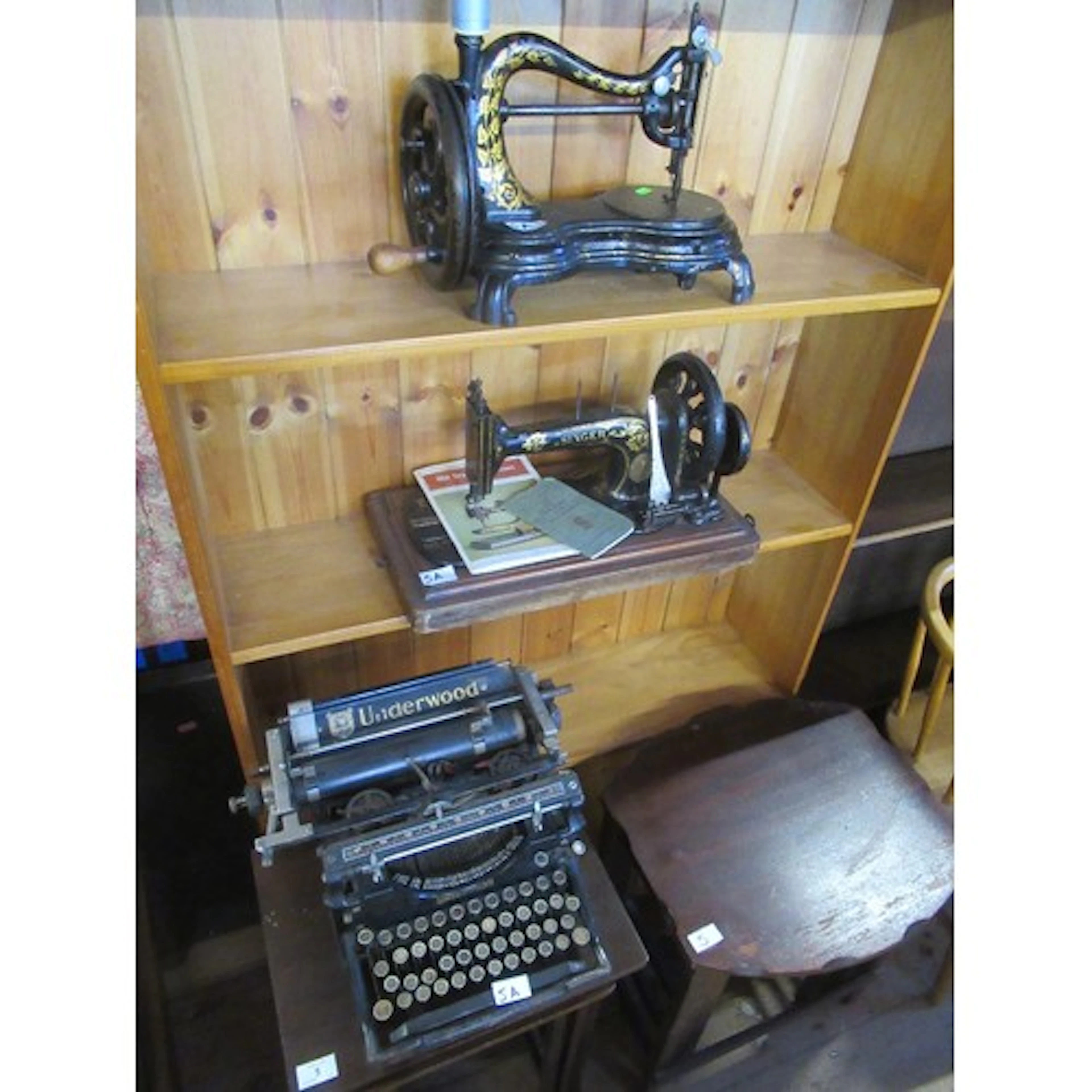 An antique sewing machine together with a Singer sewing mach...