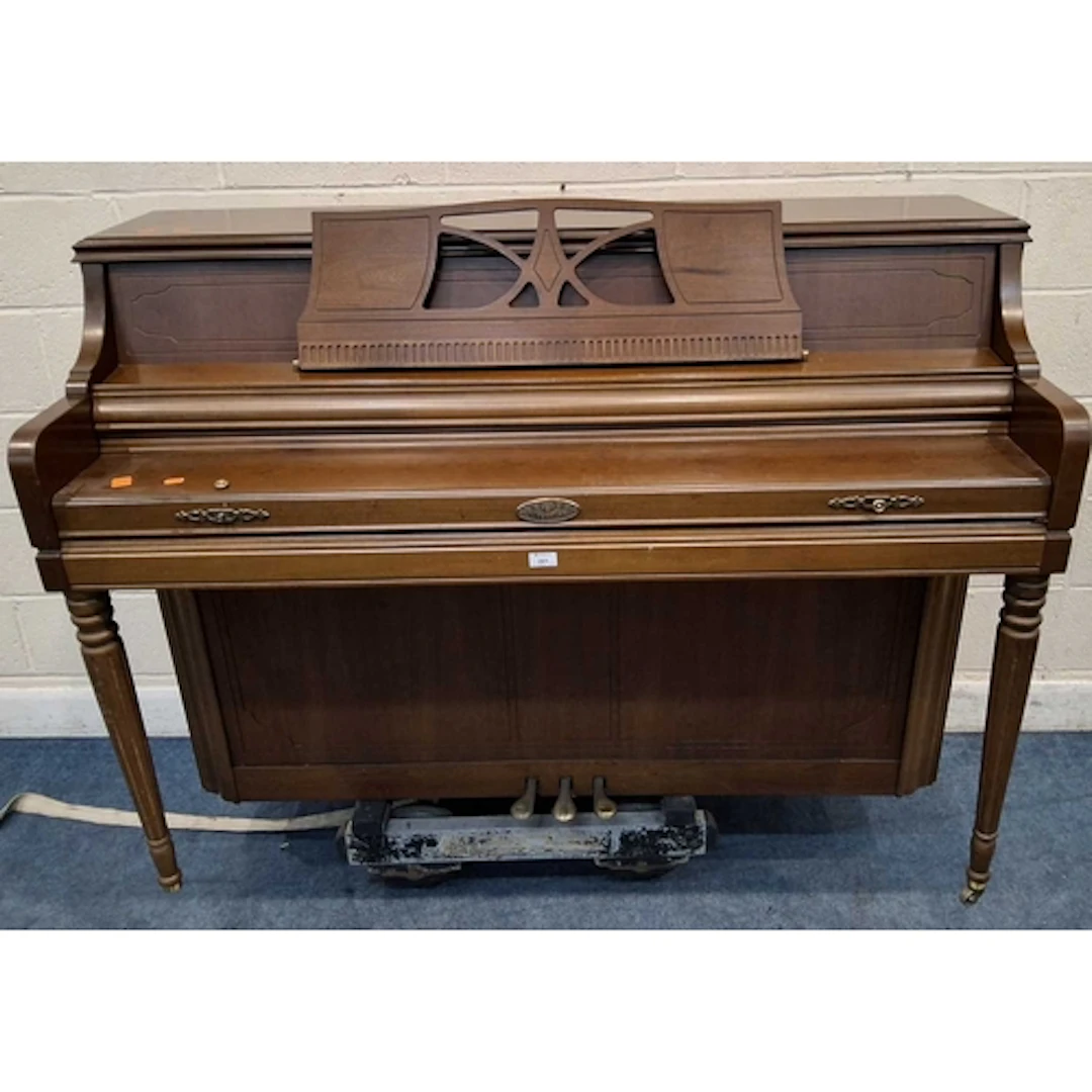 A WURLITZER UPRIGHT PIANO, with a hinged sheet music stand, ...