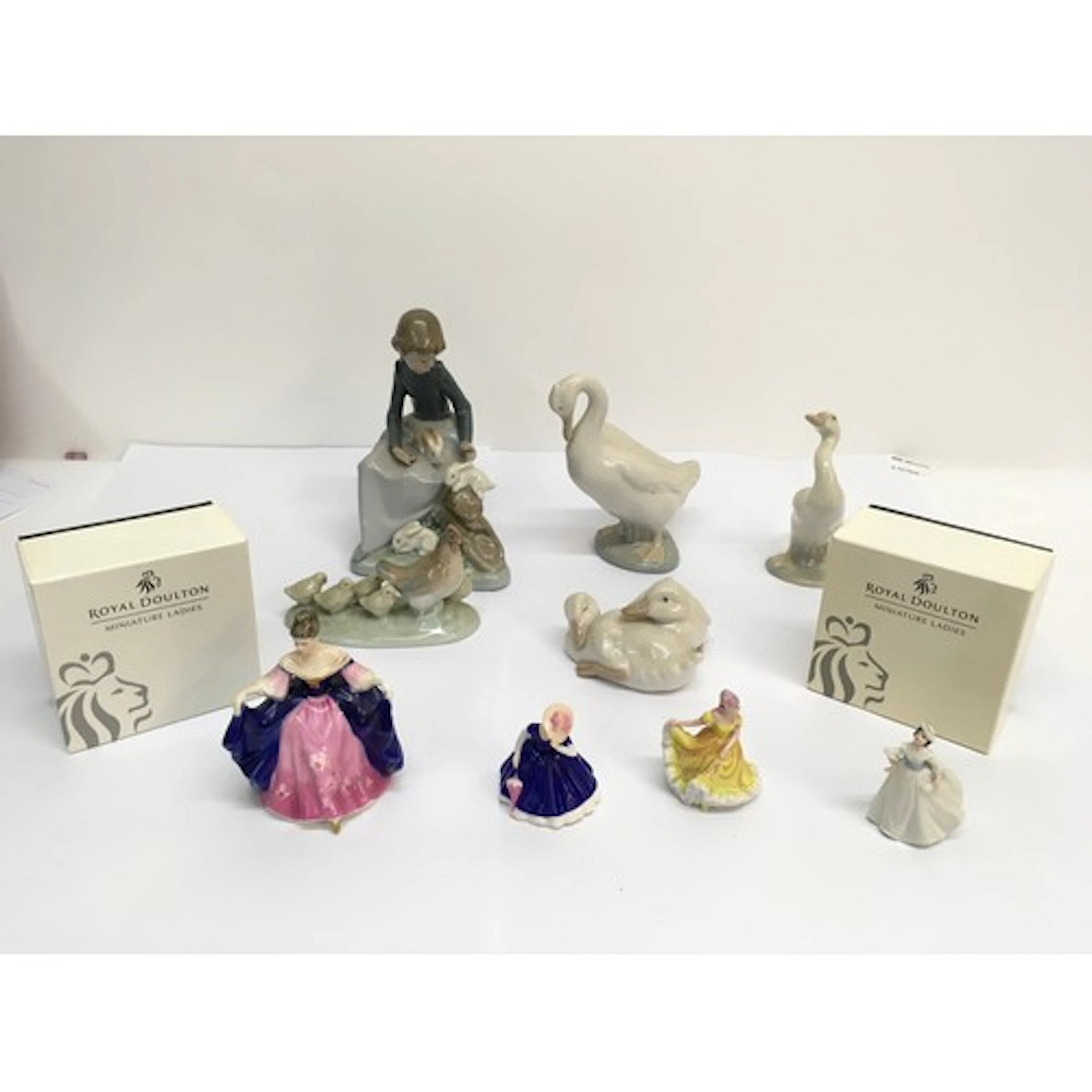 A group of Nao models and Royal Doulton miniature ladies.