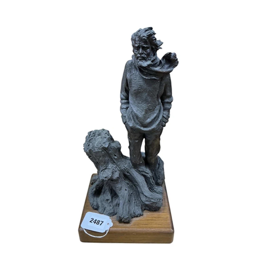 A bronzed composition figure of a man beside a tree stump, o...